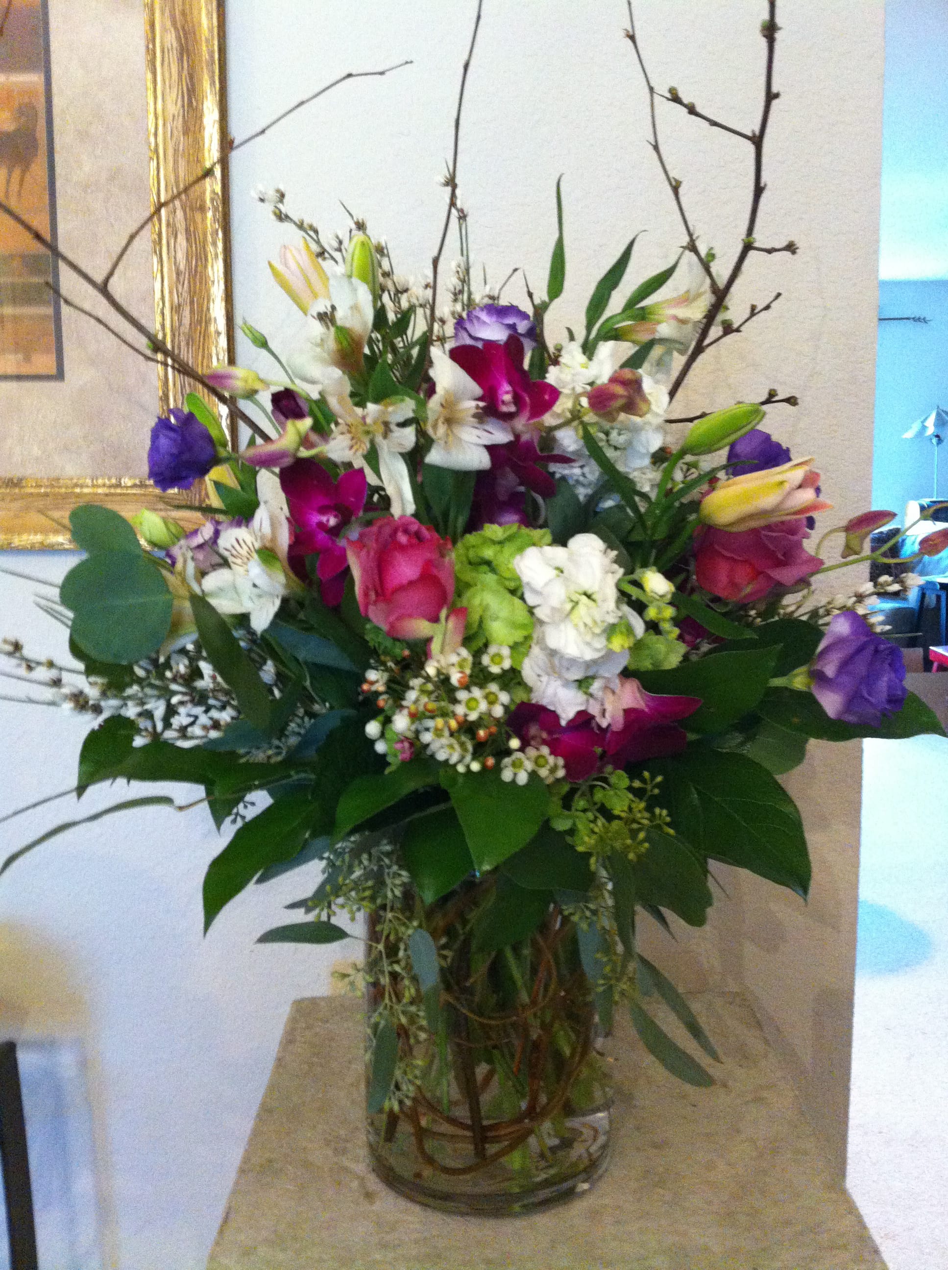 Mixed bouquet of pink, purple, white, and green flowers in a glass vase