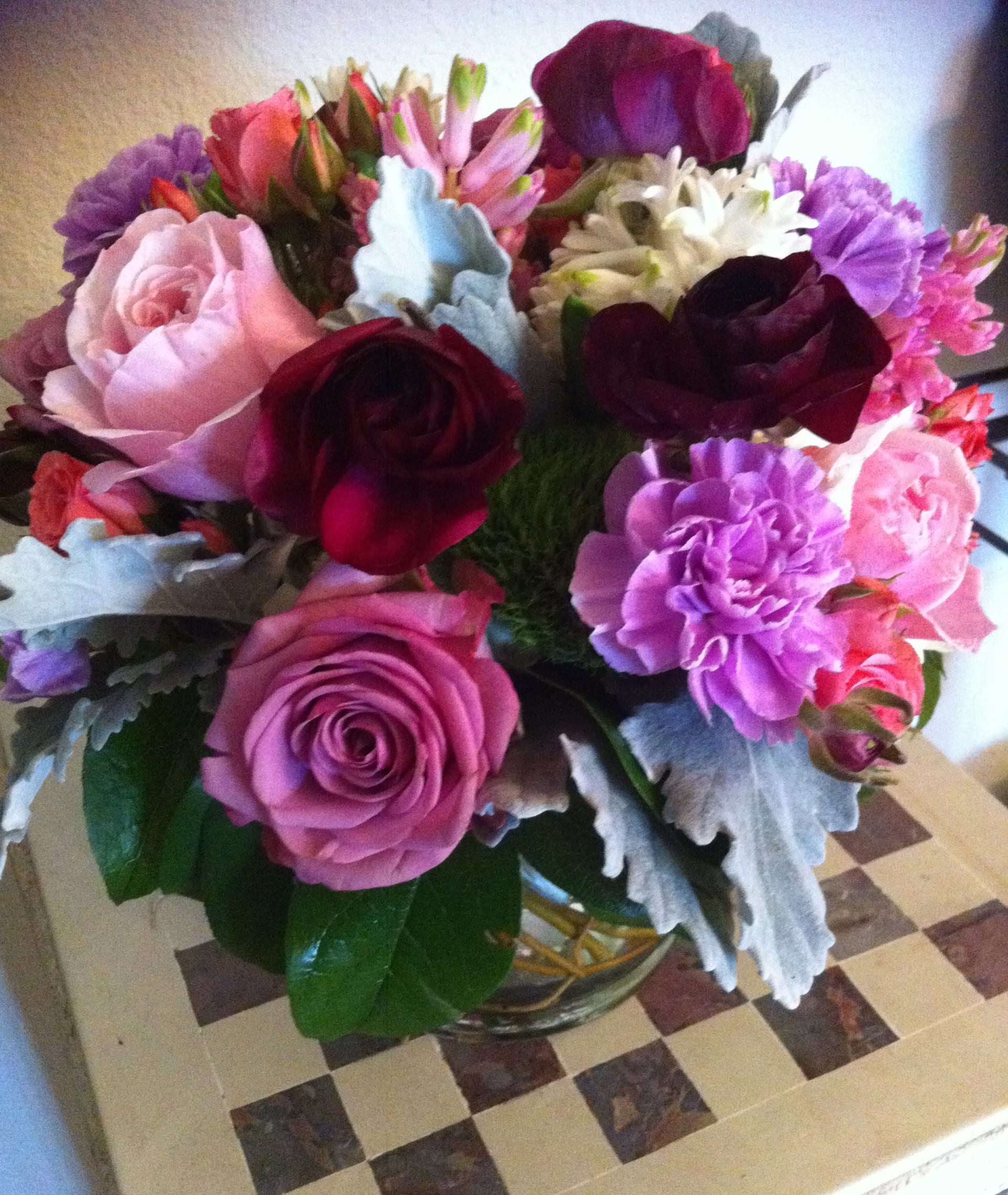 Mixed bouquet of roses, carnations, and daisies in a glass vase