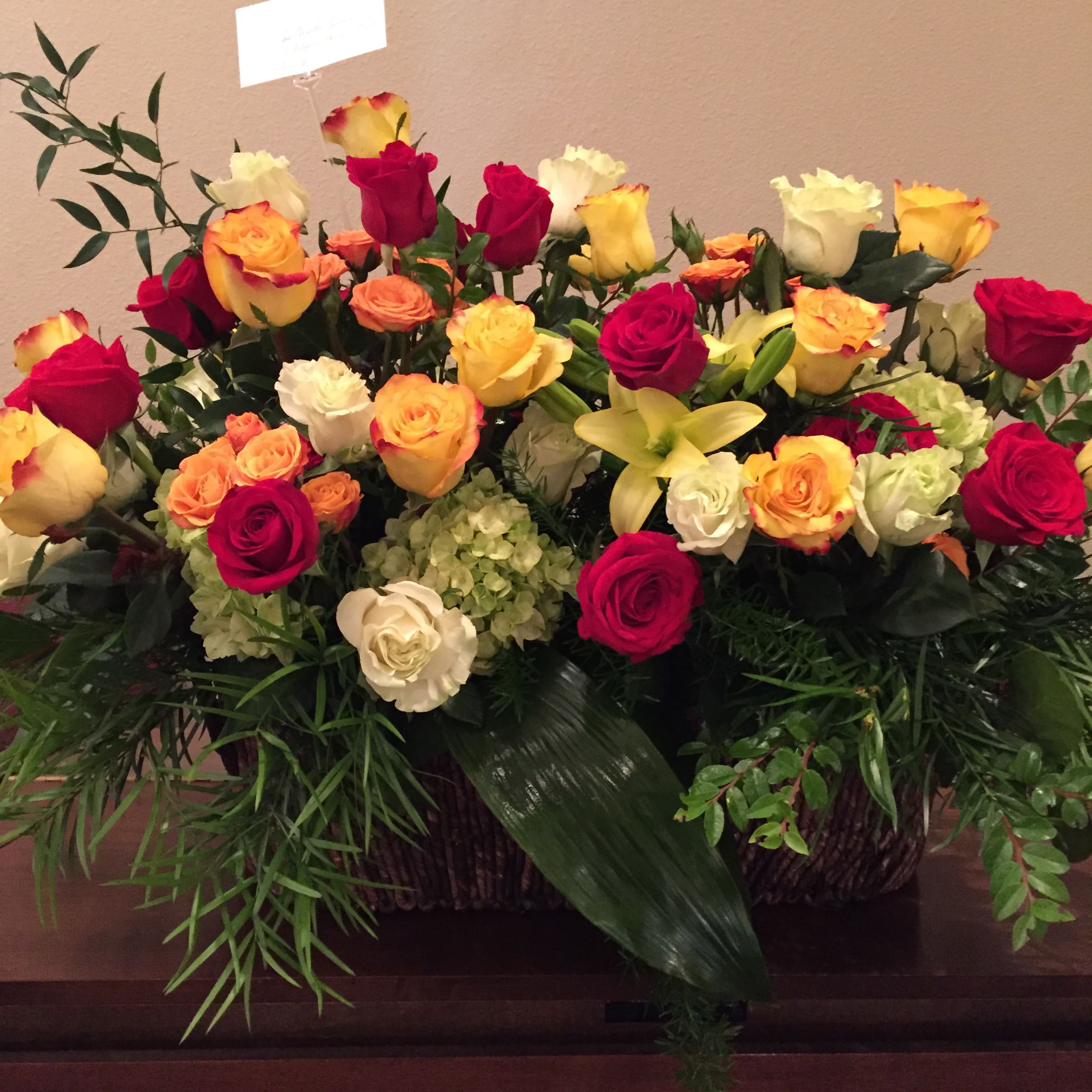 Large mixed rose arrangement with yellow lilies in a basket