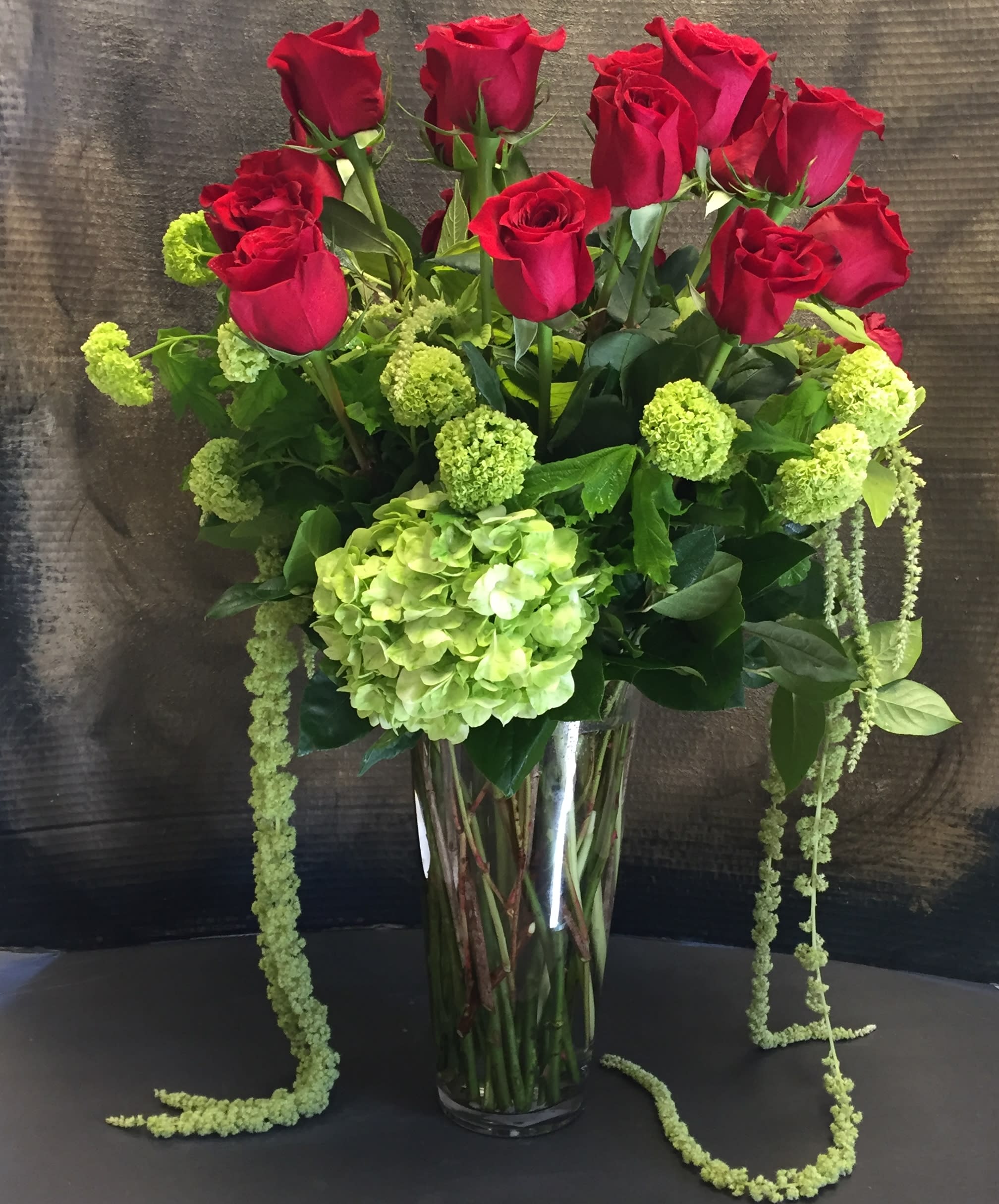 Red roses and green hydrangea in a tall glass vase