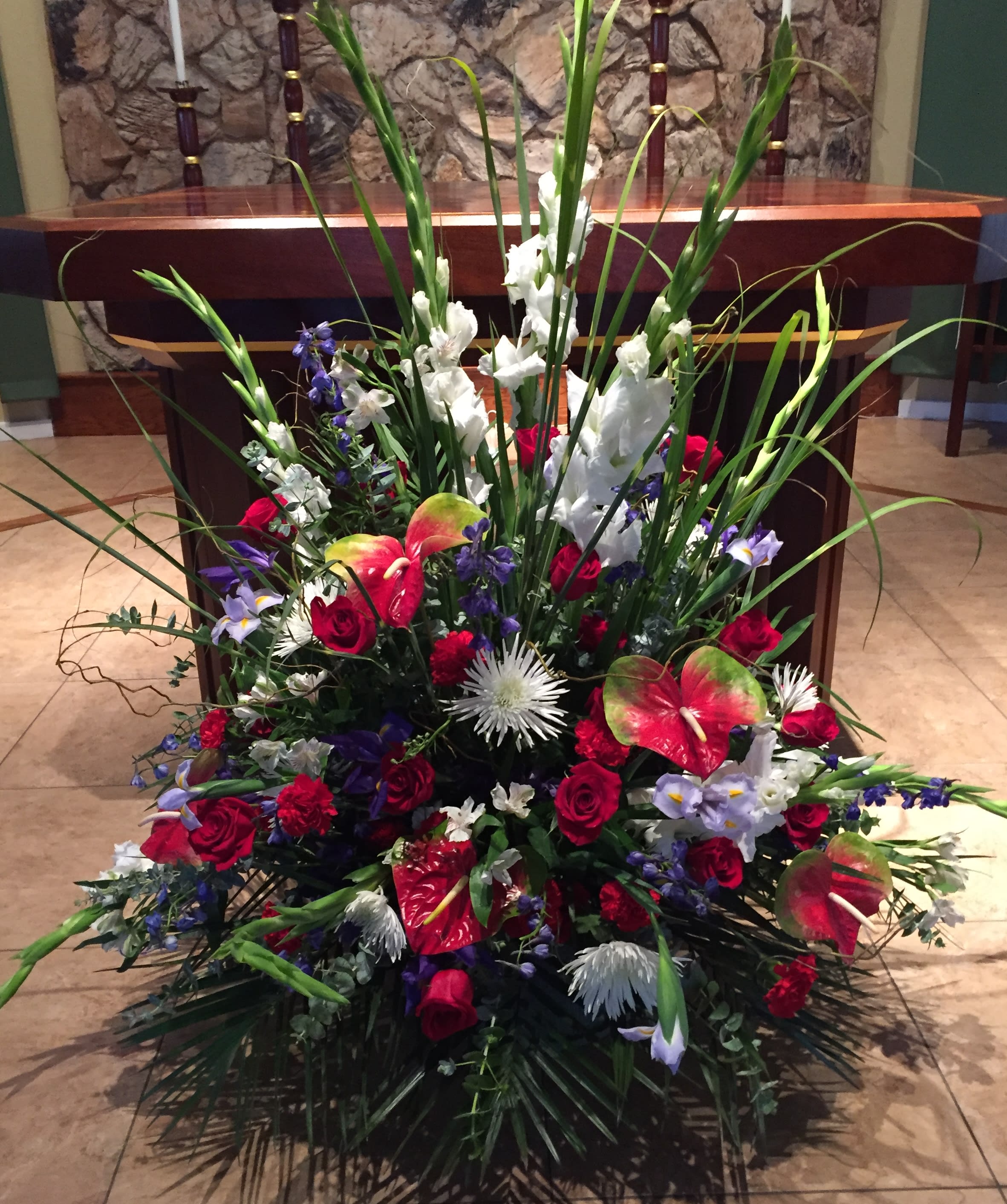 Large floral arrangement with red roses, white gladiolus, and anthuriums