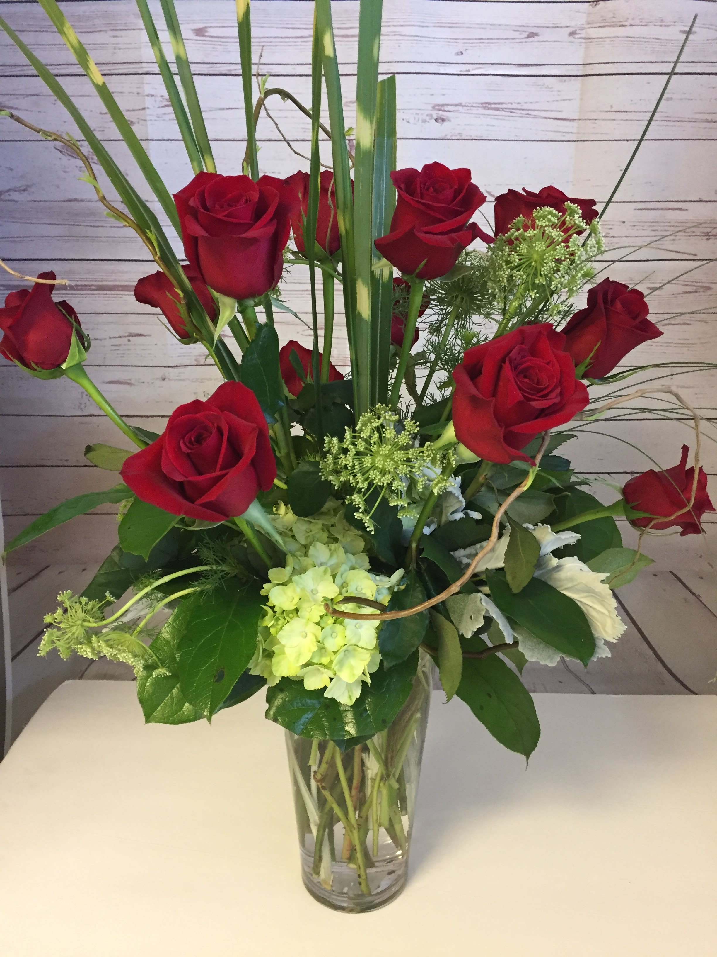 Red roses and pale green hydrangea in a clear glass vase