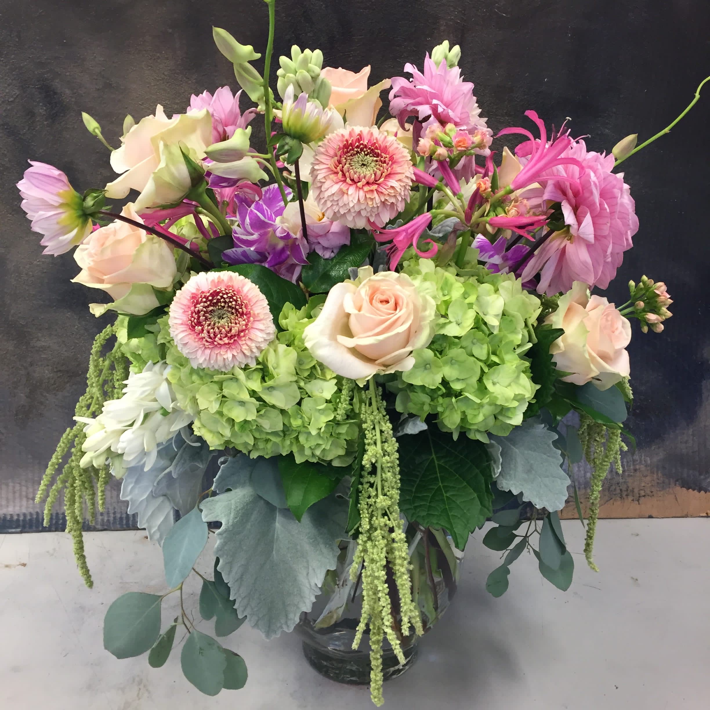 Pink and cream flowers in a glass vase with green hydrangeas