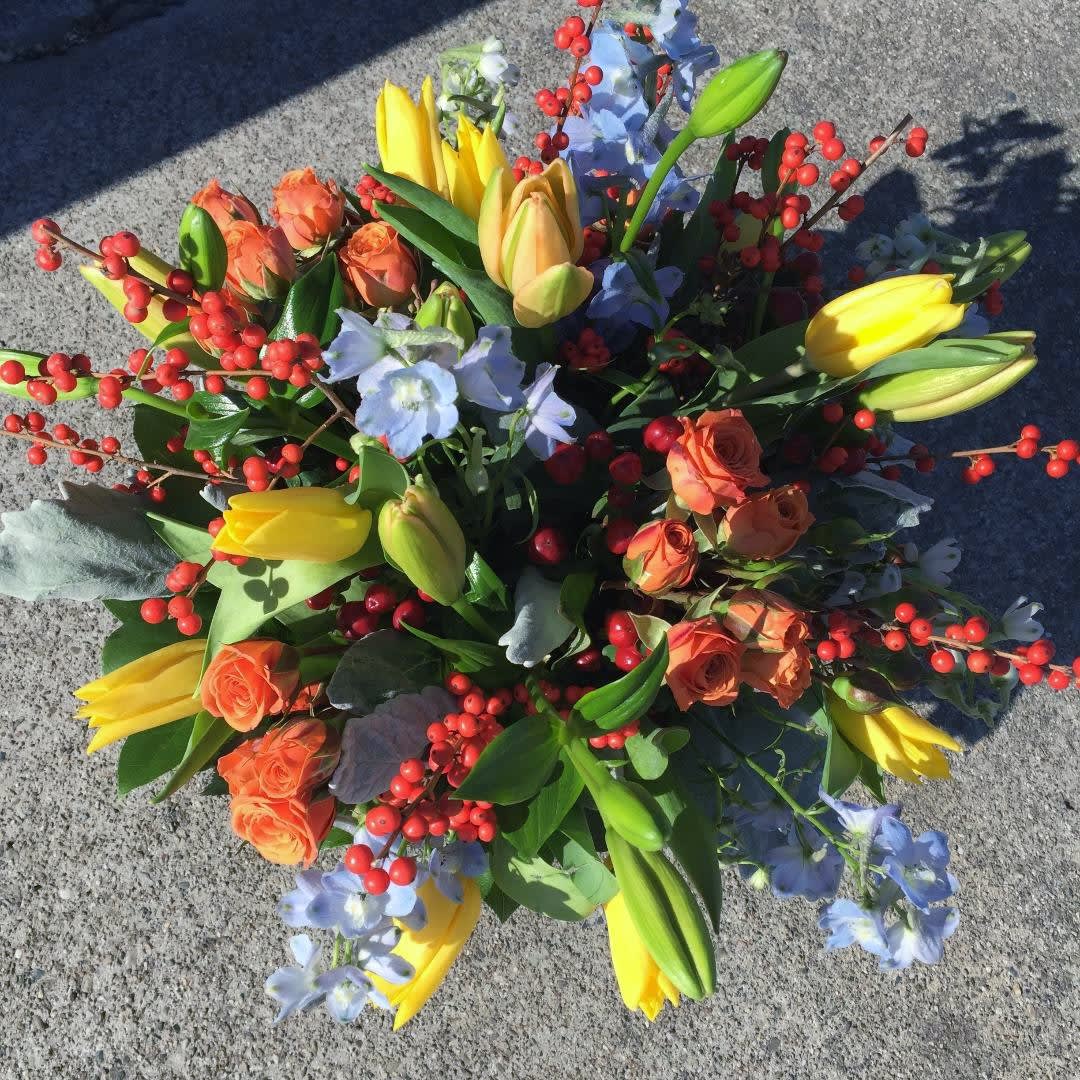 Bouquet of yellow tulips, orange roses, and blue flowers with red berry stems