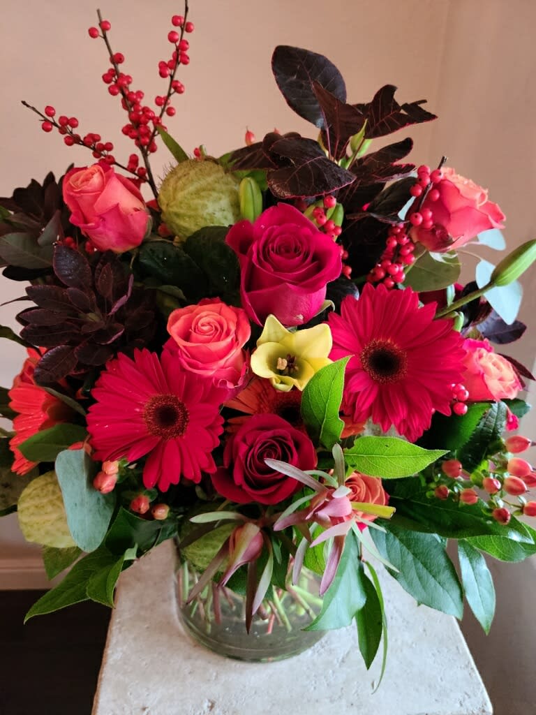 Bouquet of pink roses and red gerbera daisies in a glass vase