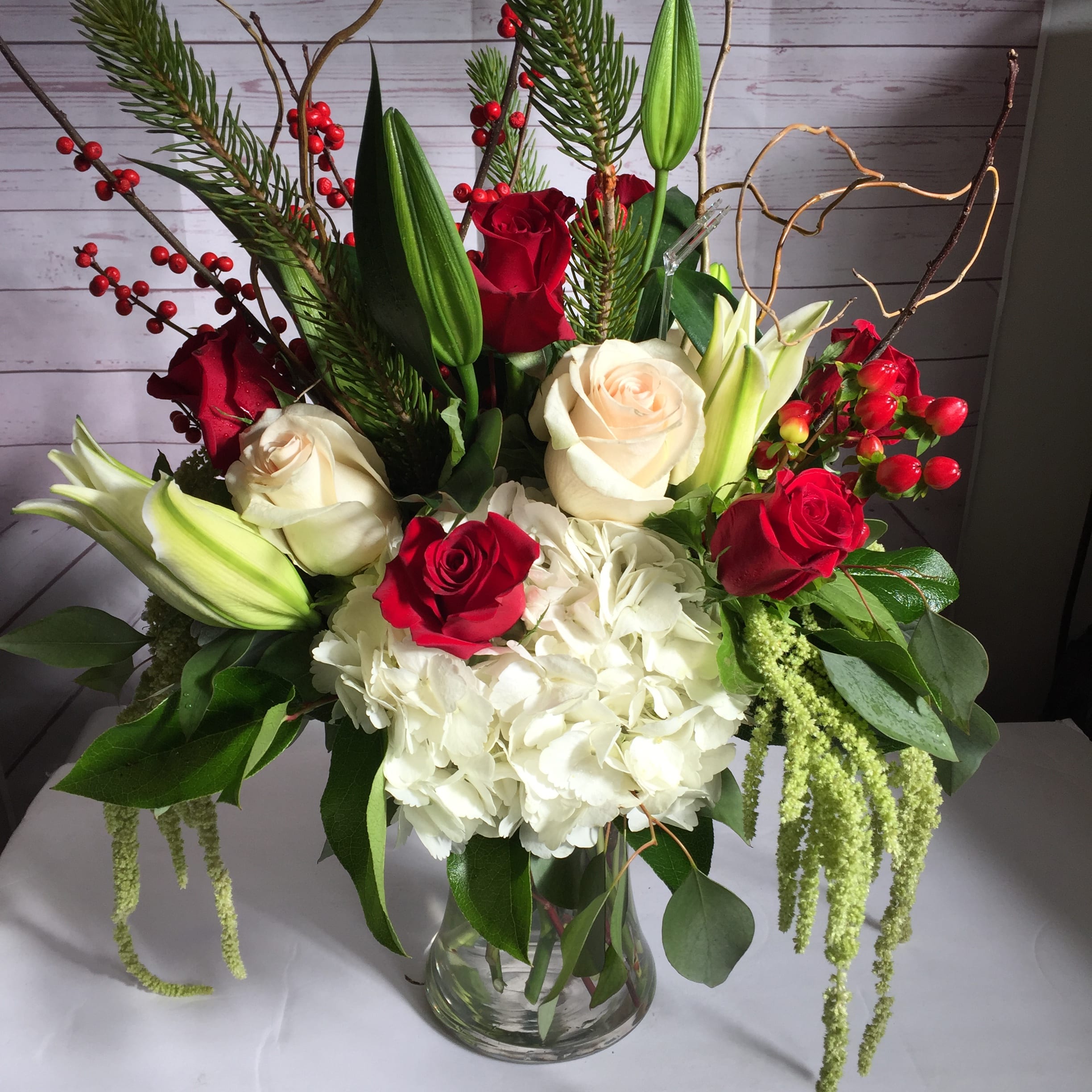 Bouquet of red and white roses with lilies and hydrangea in a glass vase