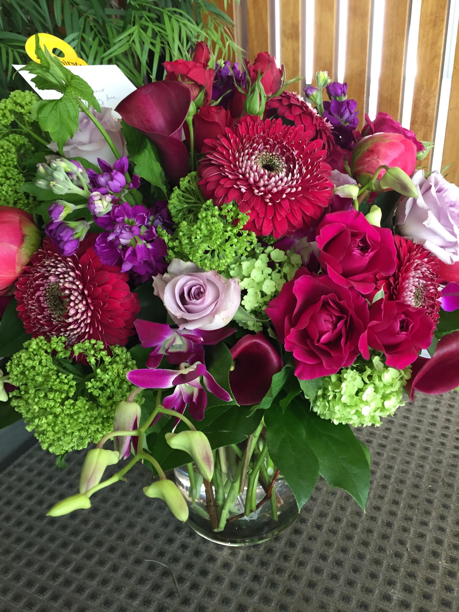Mixed bouquet of pink, purple, and green flowers in a glass vase