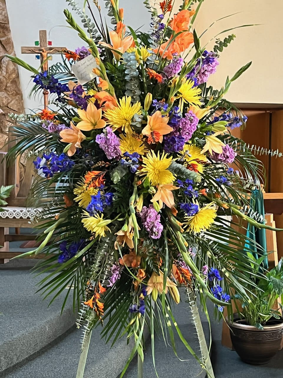 Large standing floral spray with yellow, orange, purple, and blue flowers