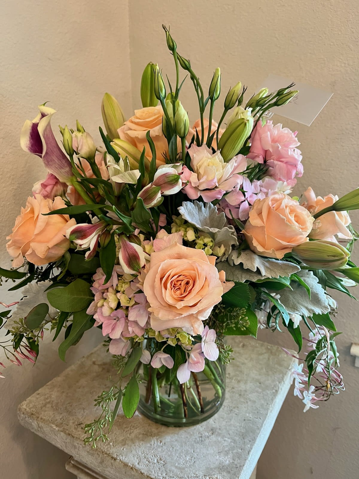 Peach roses and pink lilies in a glass vase