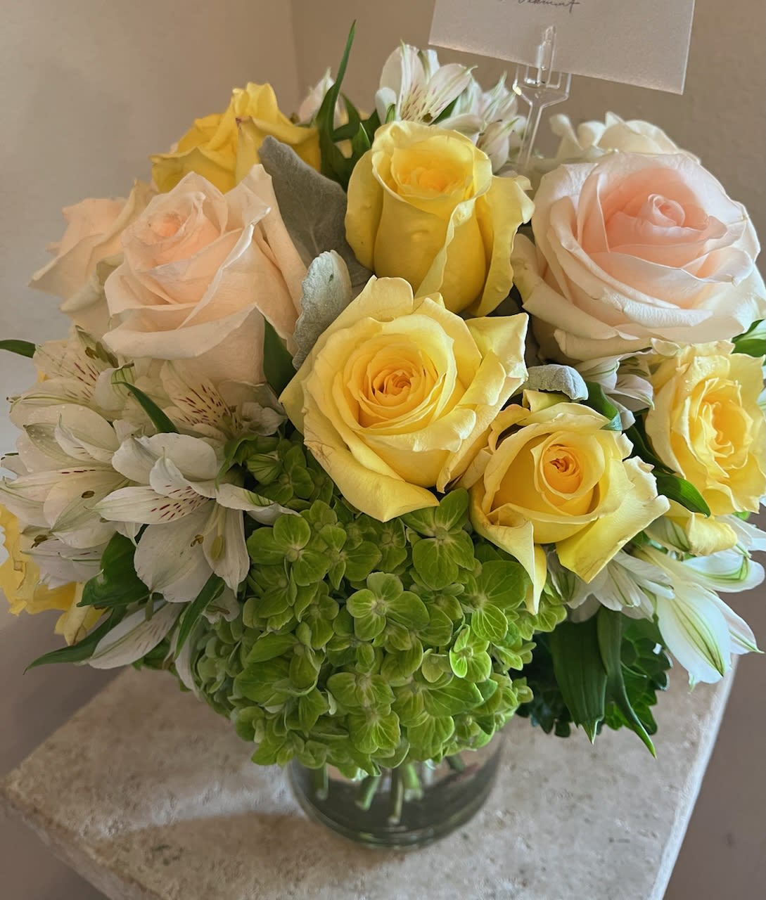 Bouquet of yellow and blush roses with white alstroemeria in a glass vase