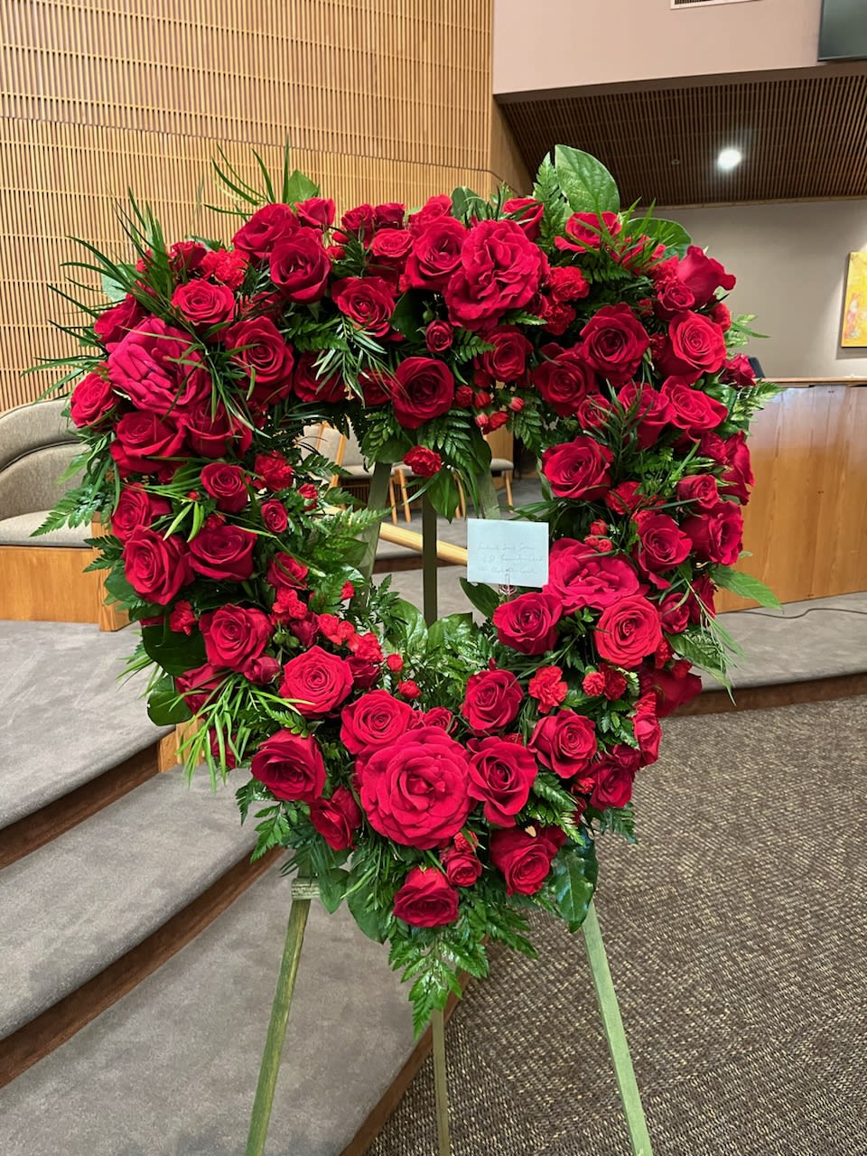Heart-shaped wreath of red roses on a stand