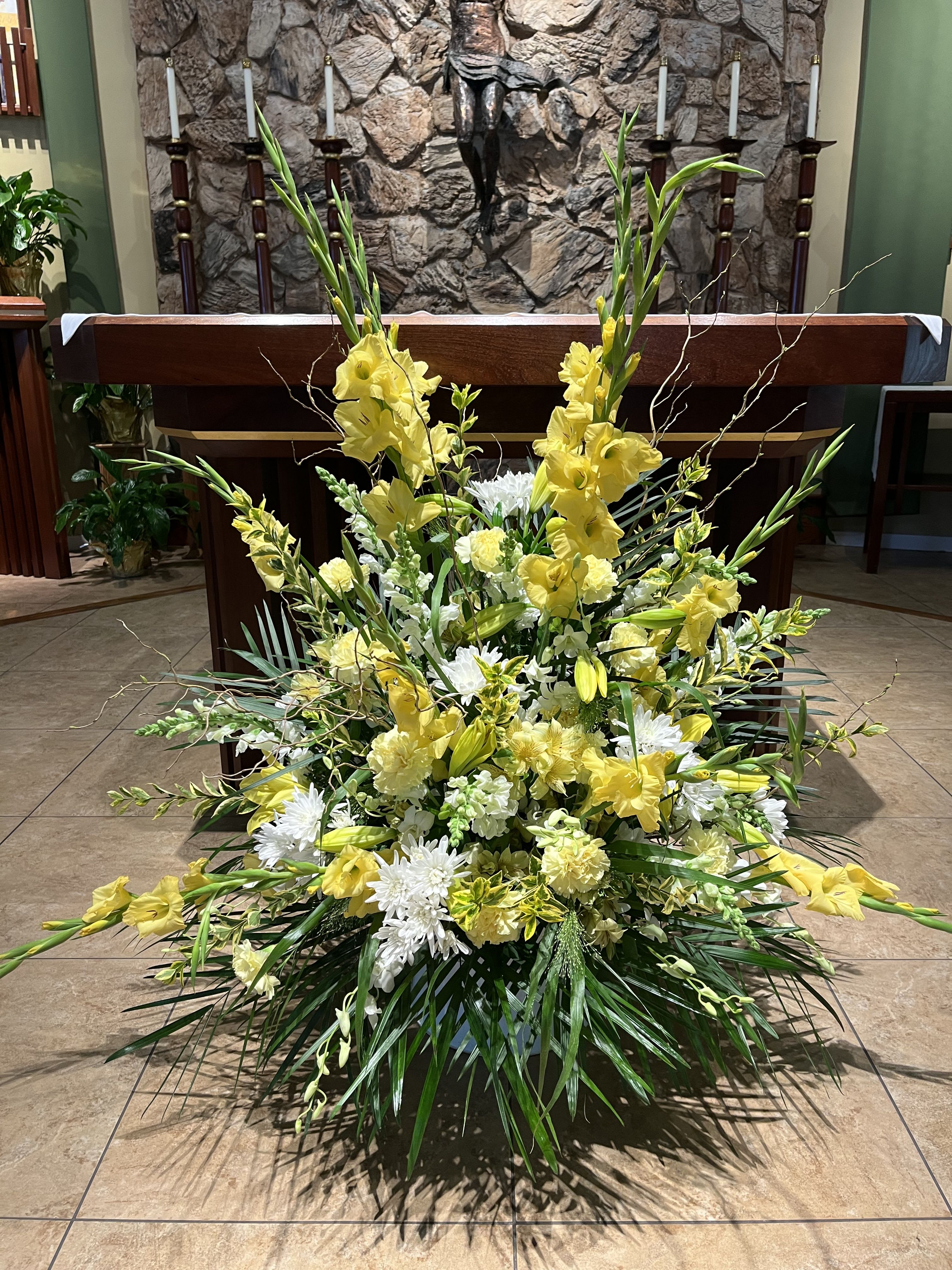 Large yellow and white floral arrangement in front of an altar