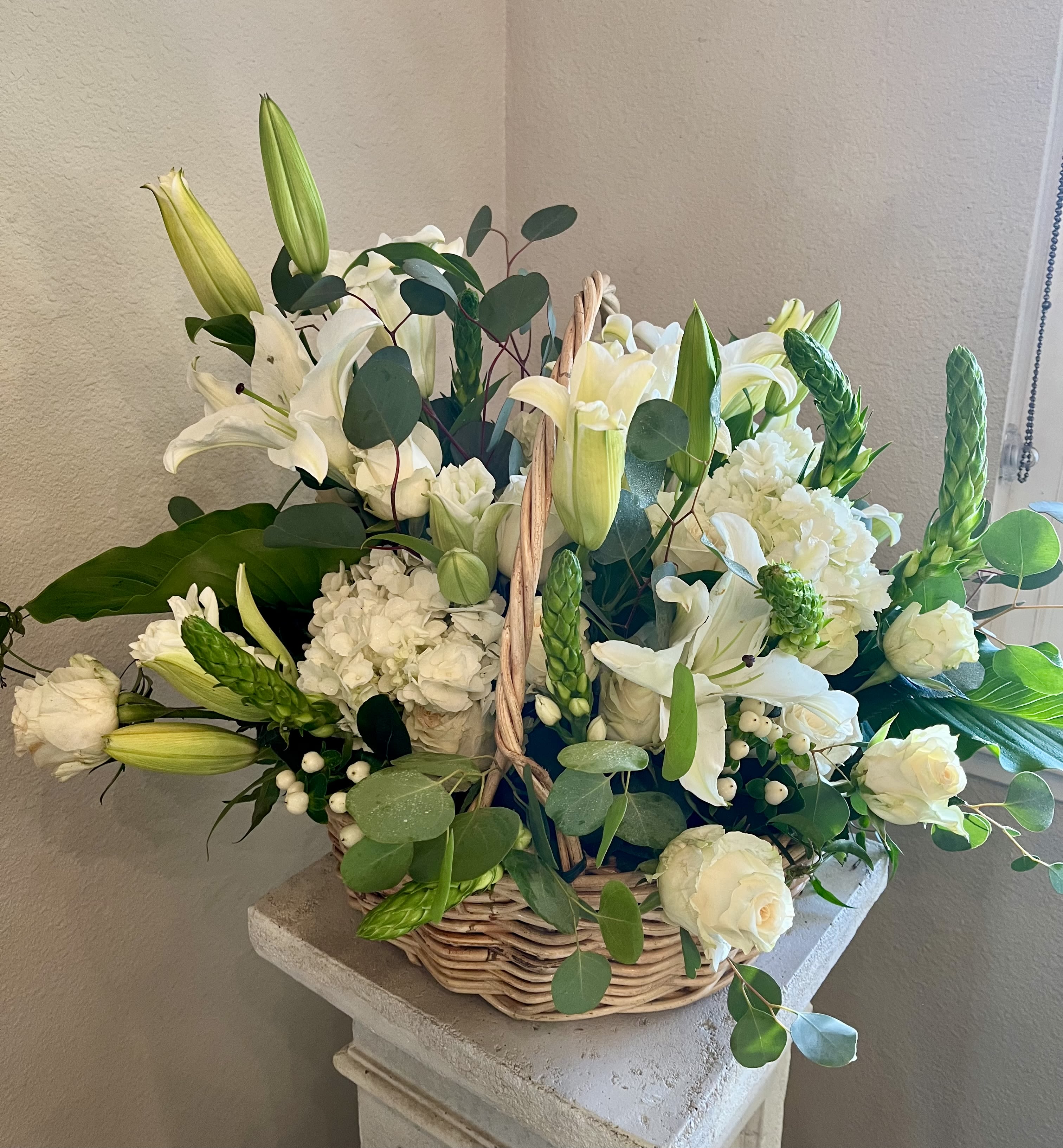 White lilies and roses arranged in a wicker basket