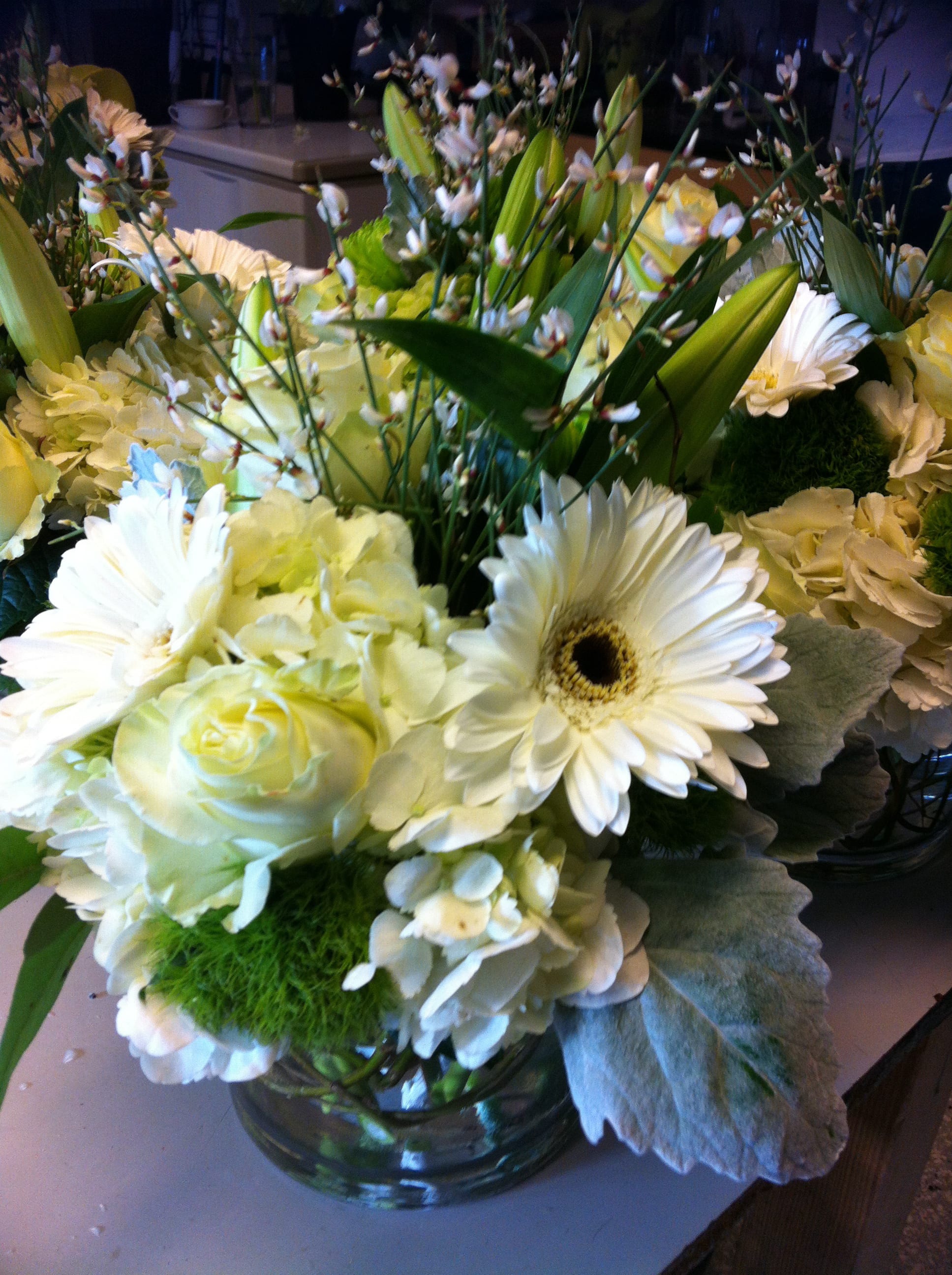 White and pale yellow floral arrangement in a glass vase