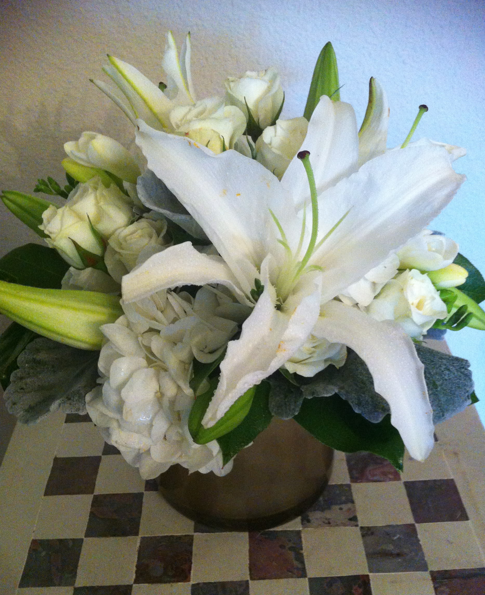 White lilies and roses arranged in a bronze vase