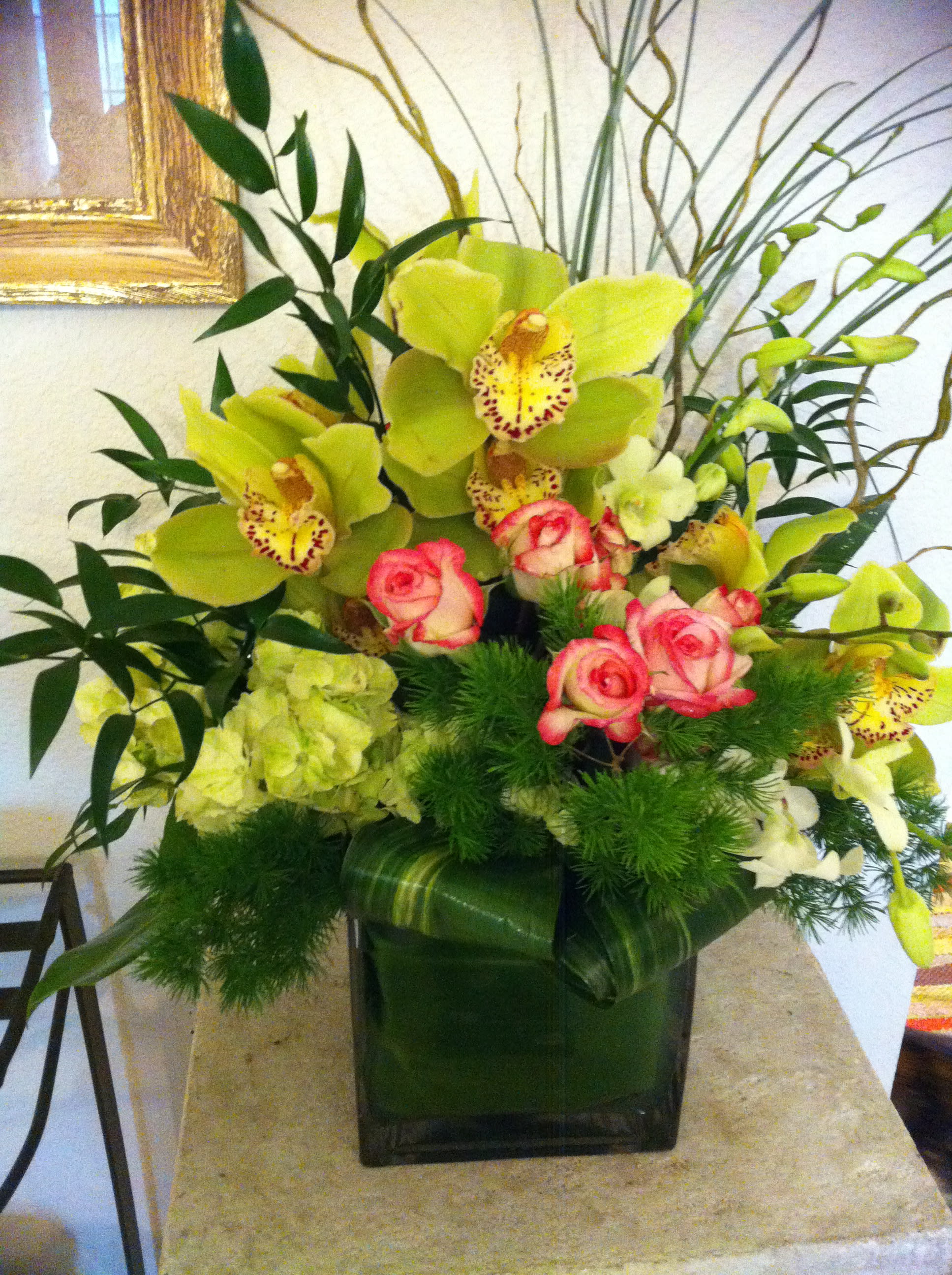 Bouquet of green orchids and pink roses in a square glass vase