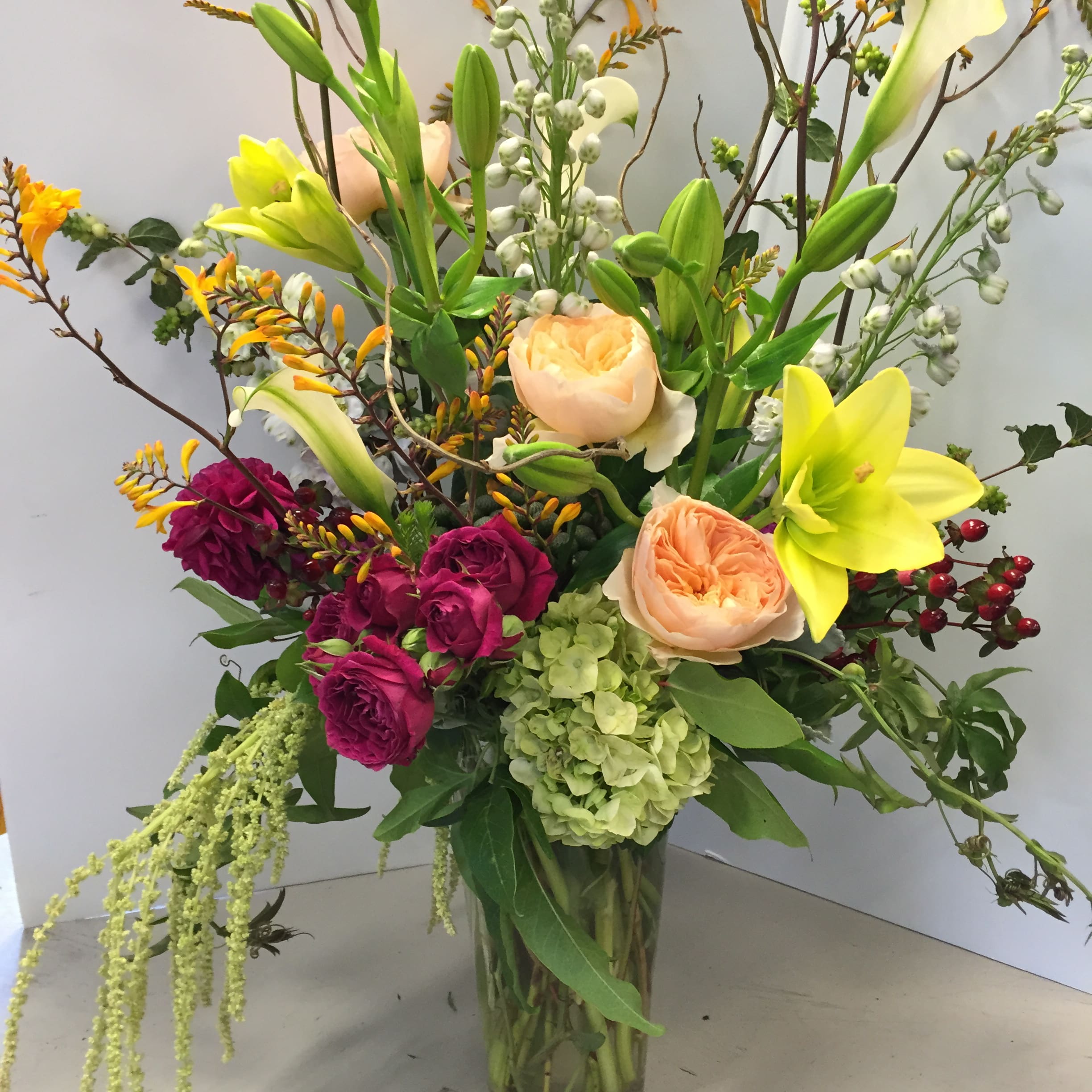 Tall mixed bouquet with lilies, roses, and hydrangea in a glass vase