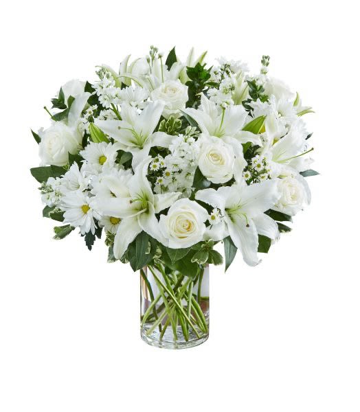 White lilies, roses, and daisies arranged in a clear glass cylinder vase