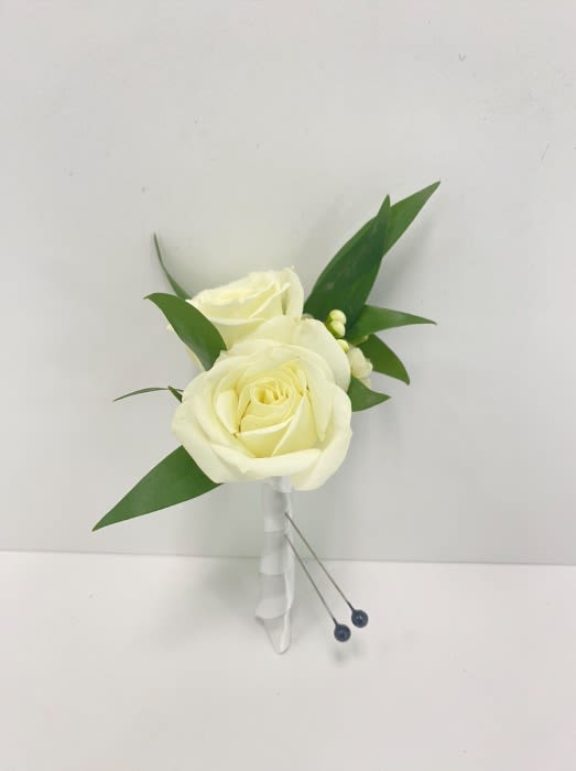 White rose boutonniere with greenery and wrapped stem on a white background