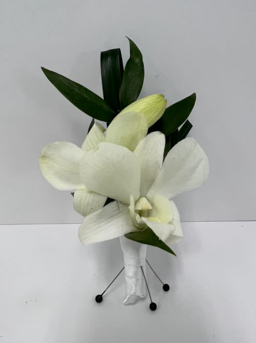 White cymbidium orchid boutonniere with wrapped stem and greenery backing