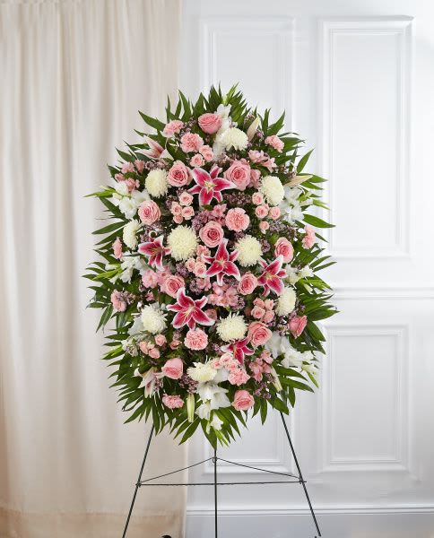Tall pink and white standing floral spray with lilies, roses, and mums on a metal easel