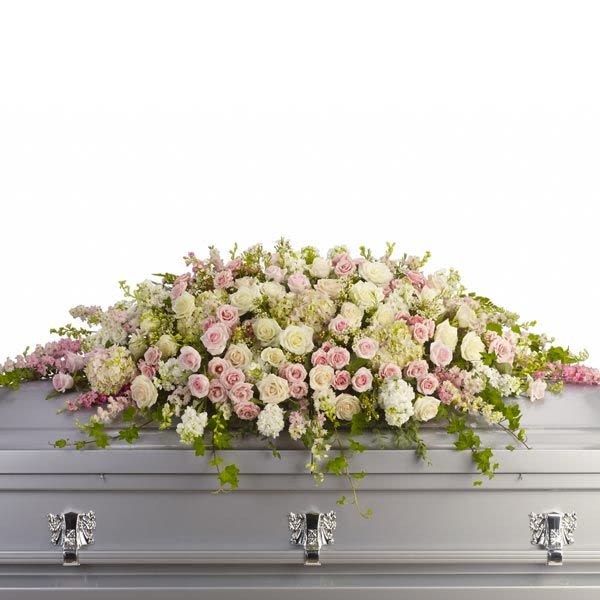 Pastel pink and white rose casket spray draped across a silver casket.
