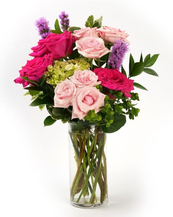 Arrangement of hot pink and light pink roses with green blooms in a clear glass cylinder vase