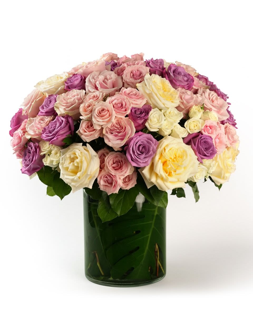 Large dome of pastel roses in a leaf-lined glass cylinder vase