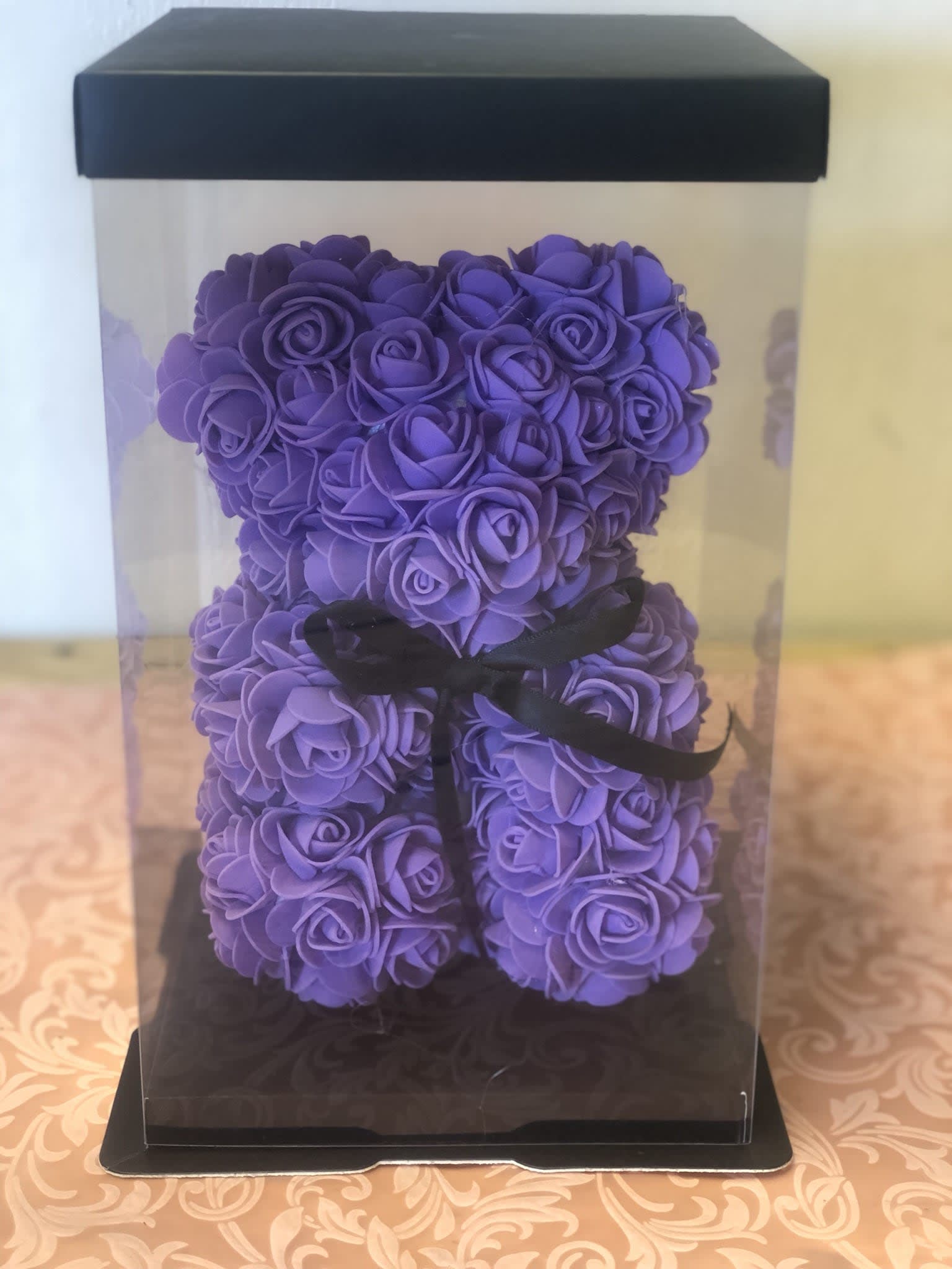Purple rose-shaped teddy bear in a clear gift box with a black ribbon