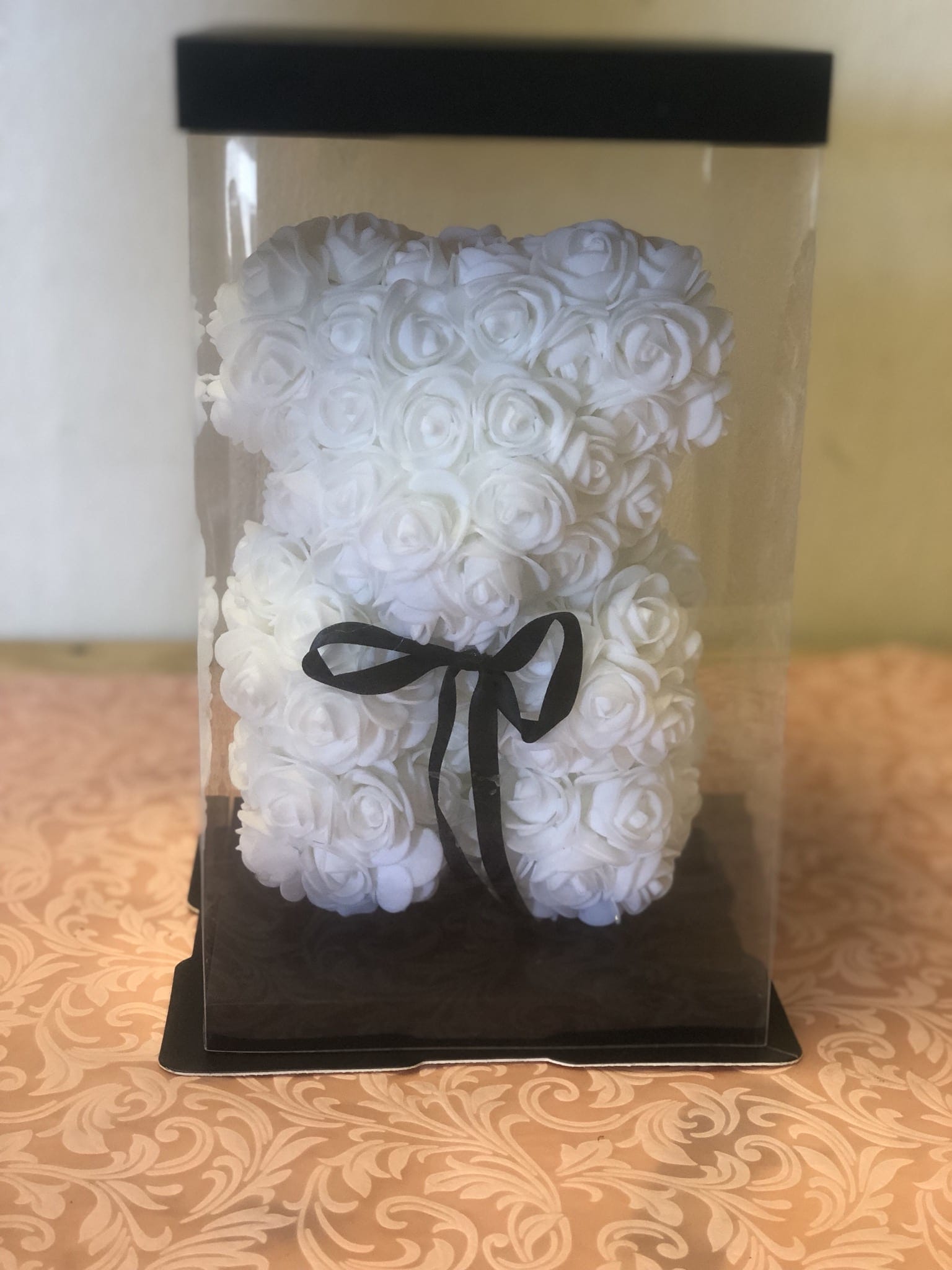 White rose teddy bear in a clear display box with a black ribbon