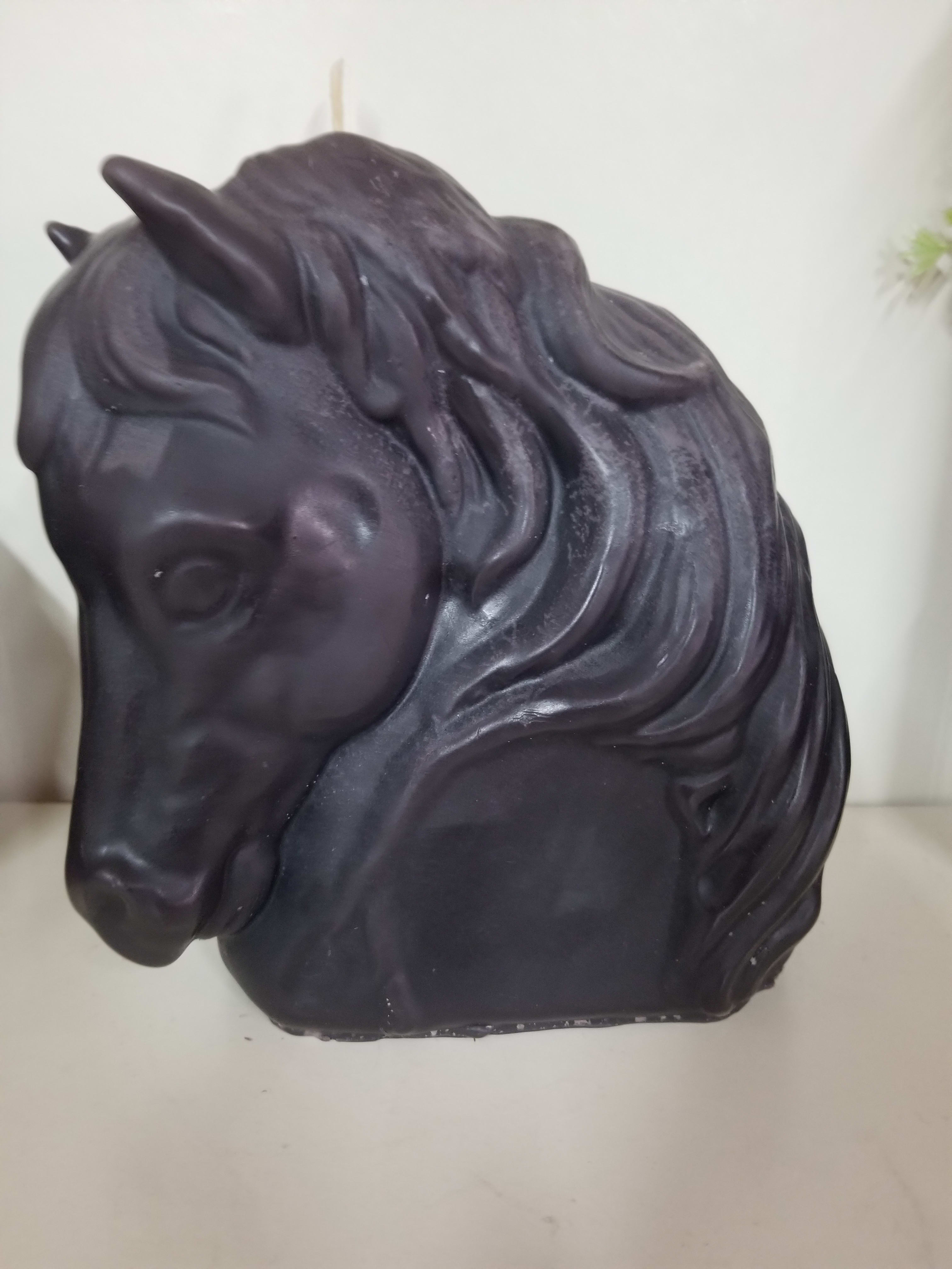 Black horse head sculpture on a white surface