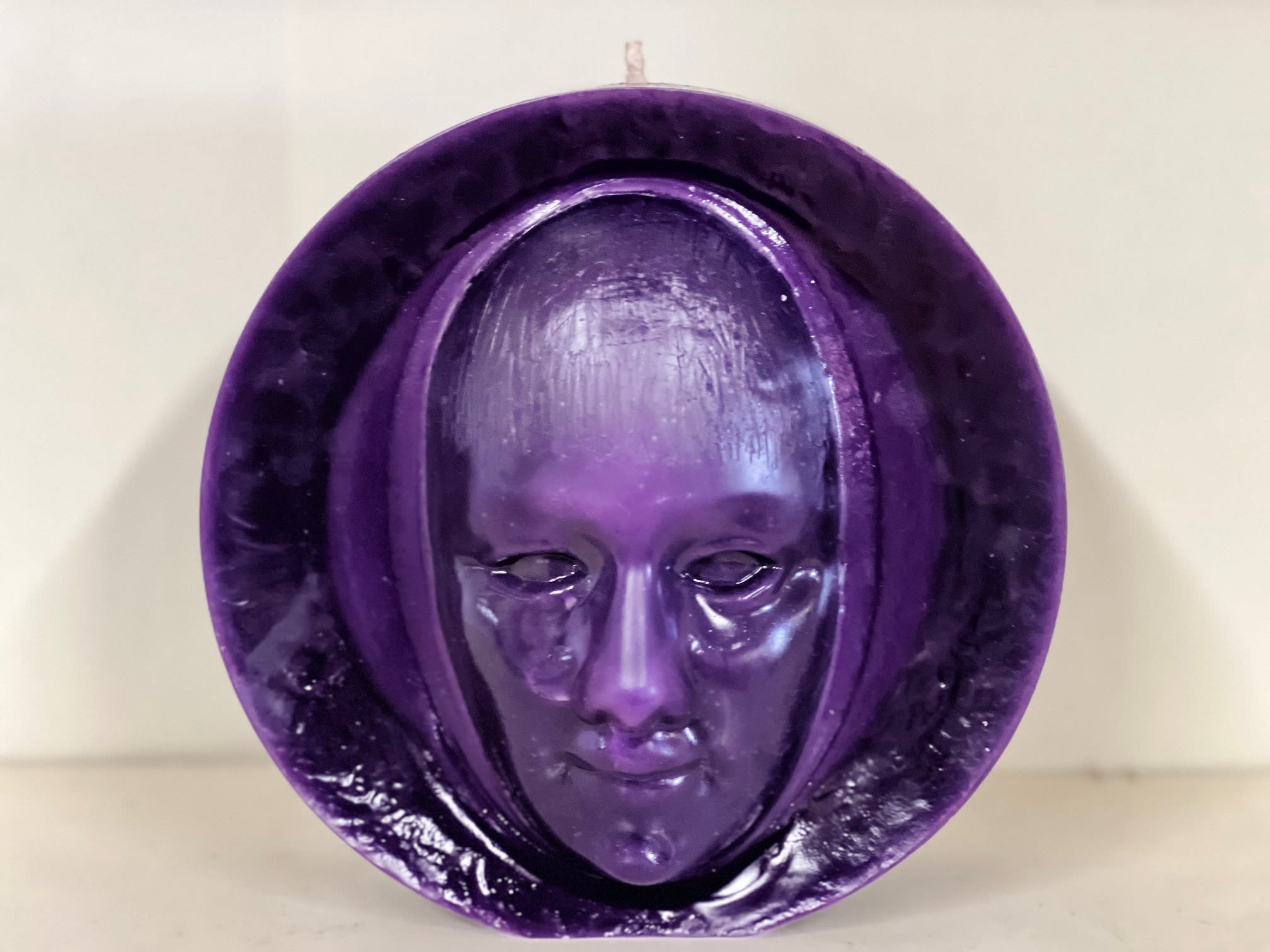 Purple decorative mask sculpture with a face in the center