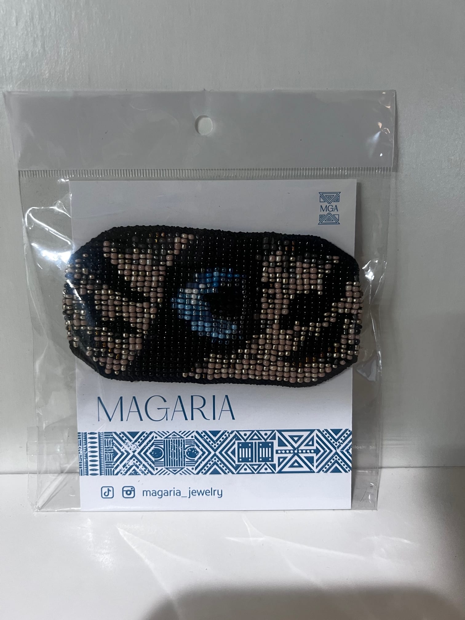 Beaded black hair accessory in plastic packaging