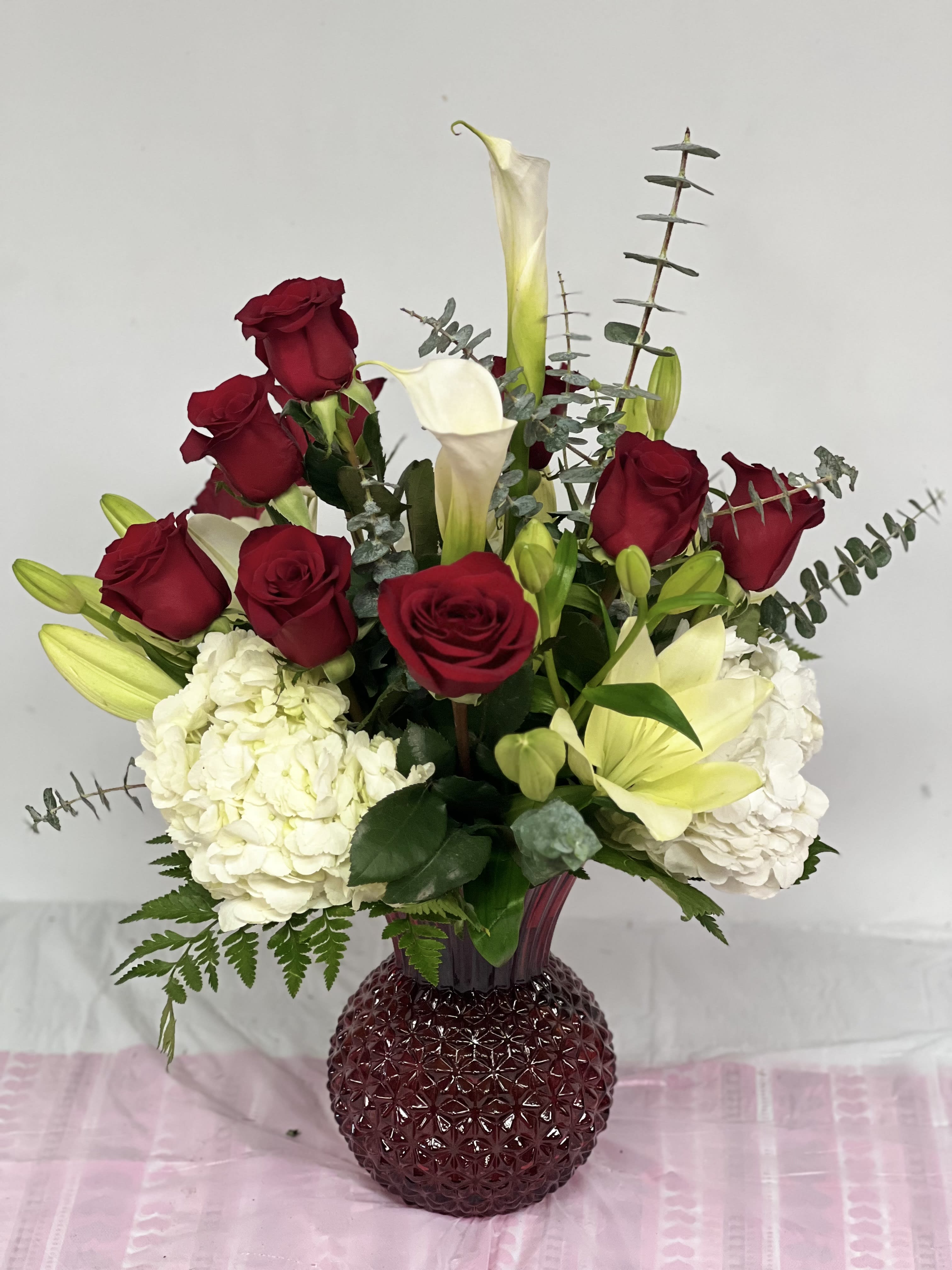 Red roses and white calla lilies in a burgundy vase