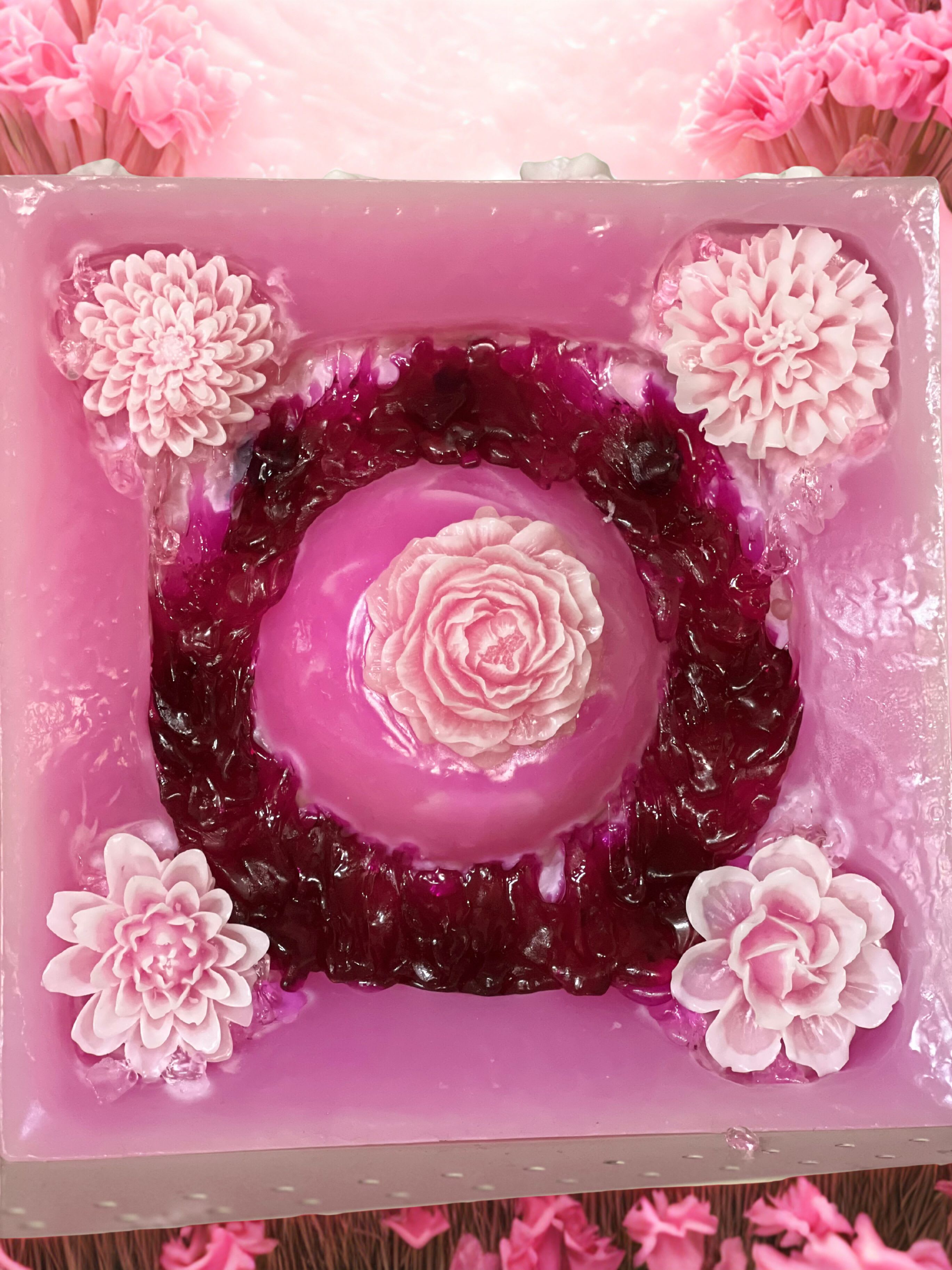 Pink floral cake with layered blossoms and a central rose