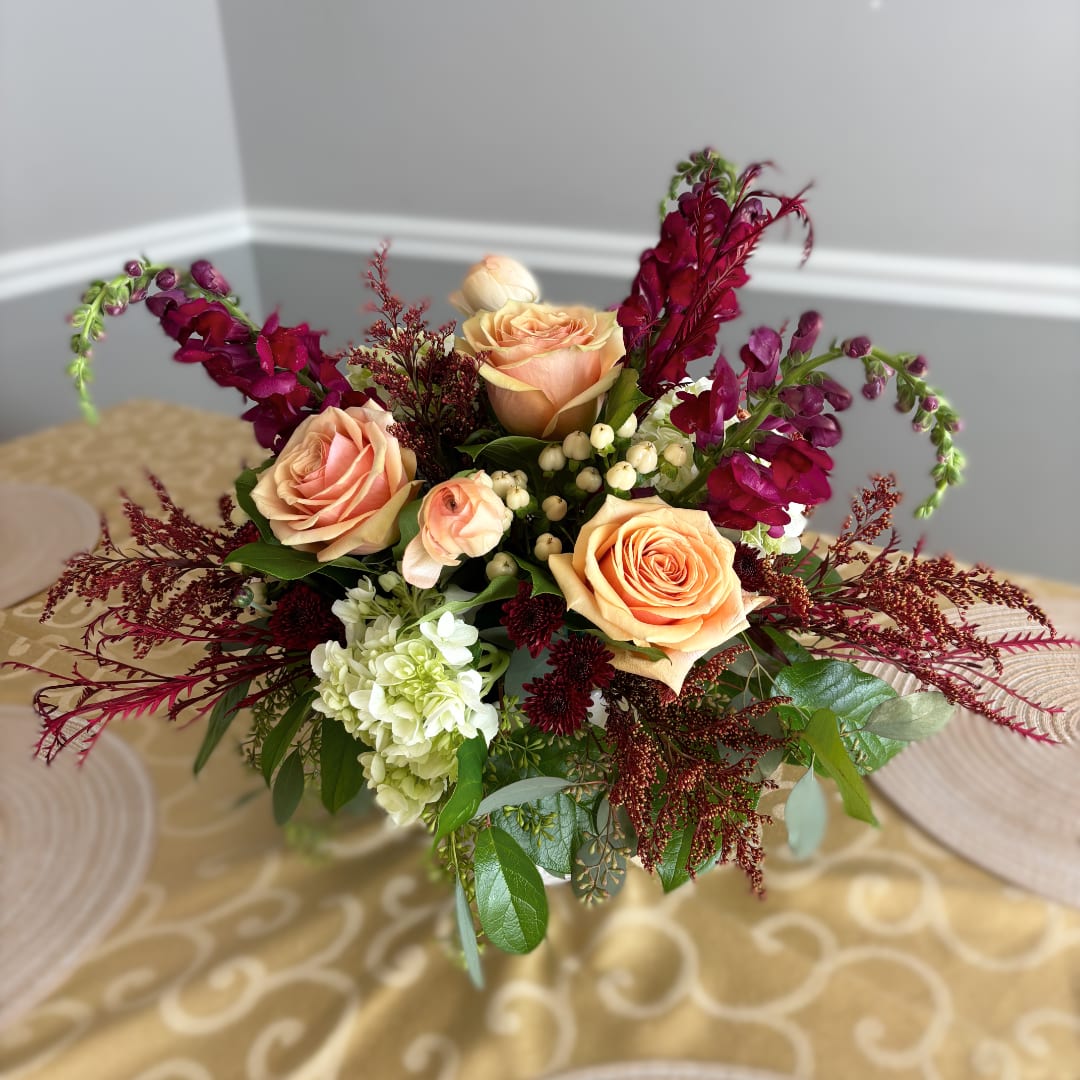 Peach roses with burgundy flowers in a low arrangement
