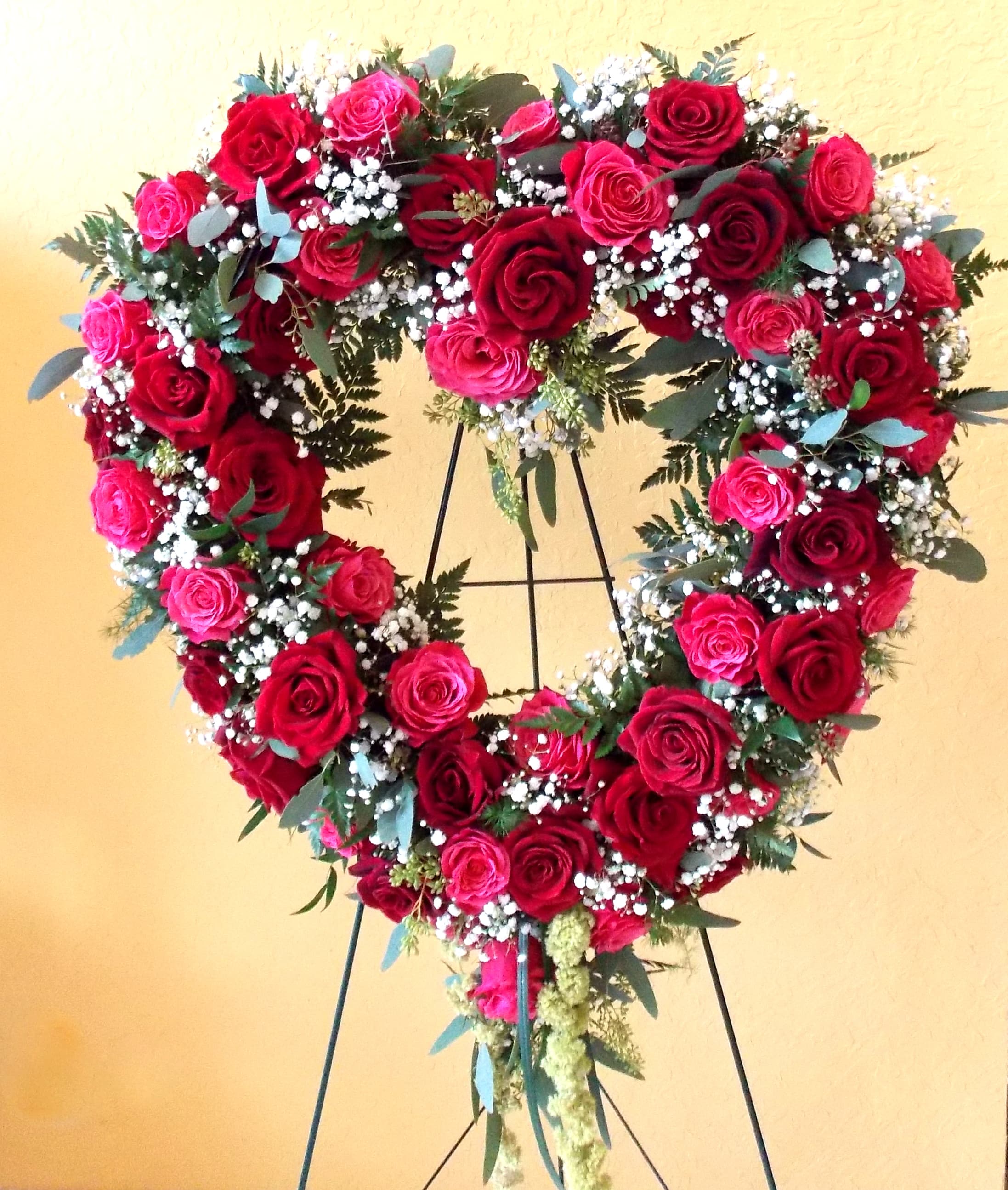 Heart-shaped rose wreath on a stand with red and pink roses