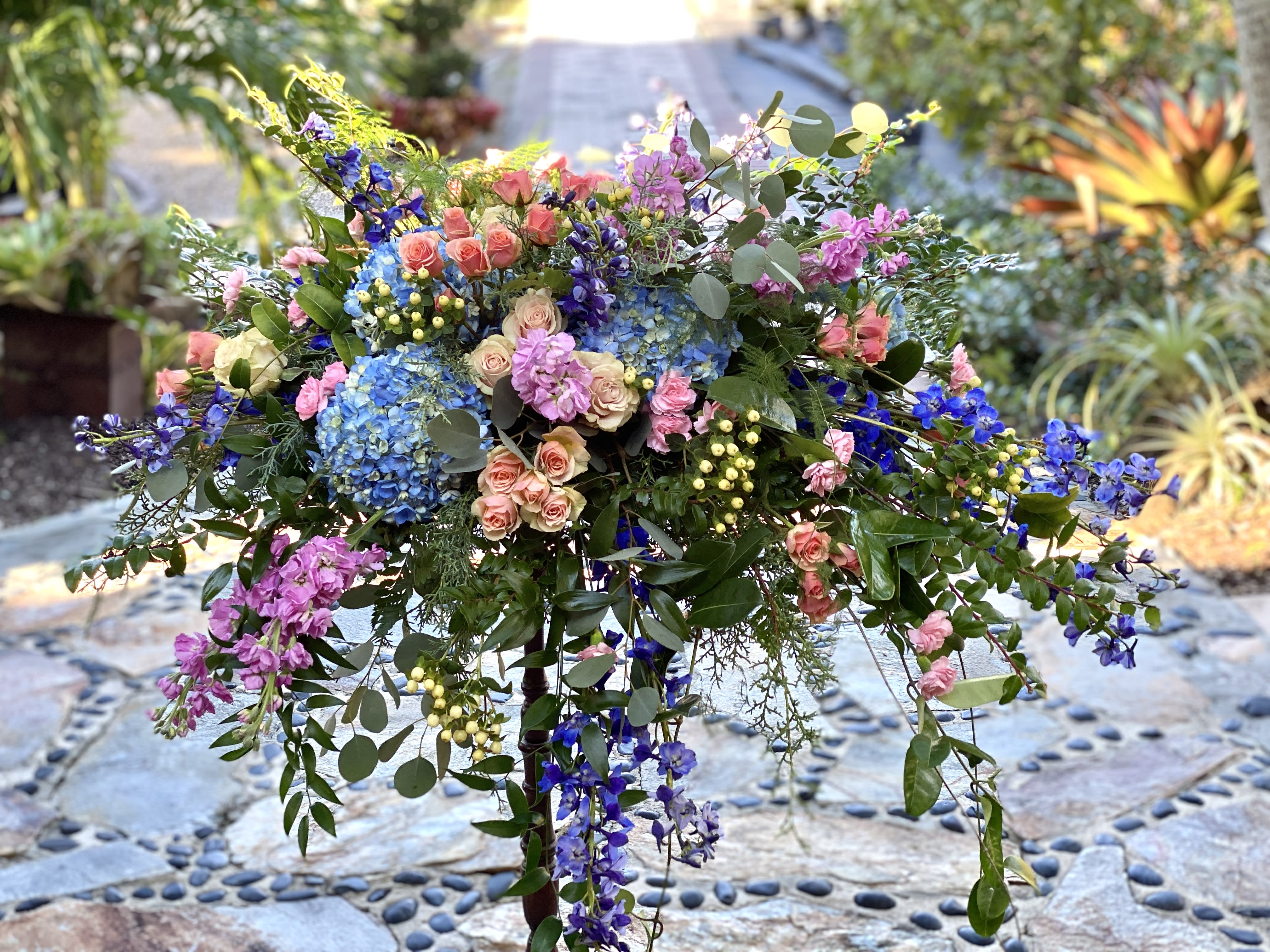 Large colorful floral arrangement with roses, hydrangeas, and hanging blooms