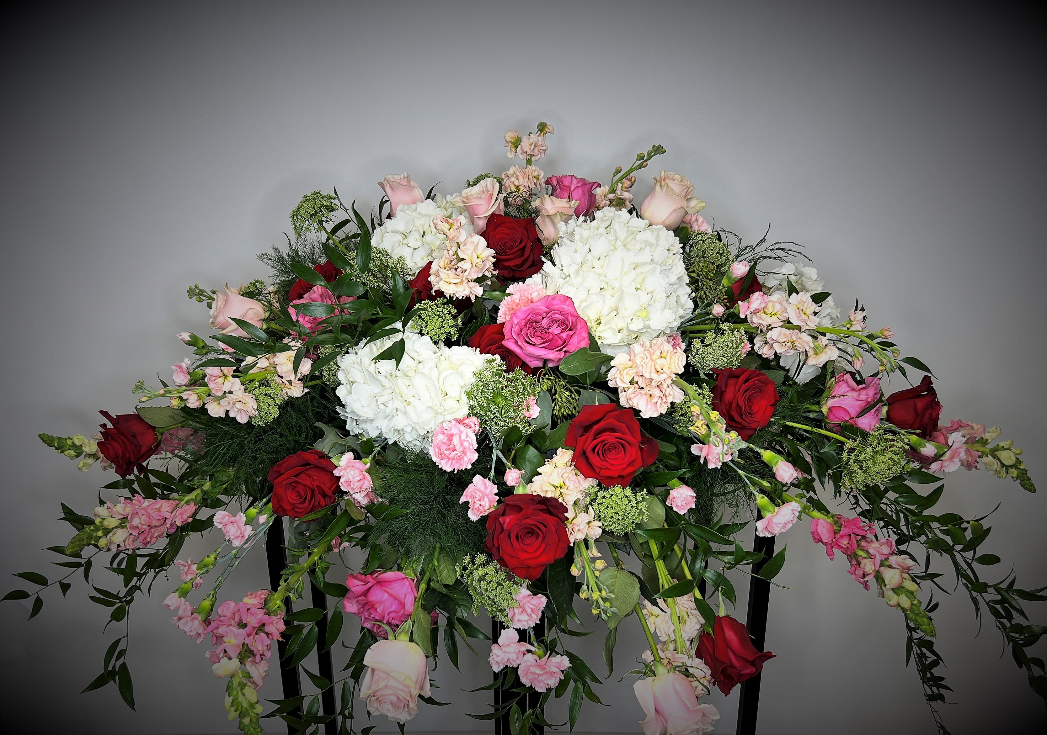 Large arrangement of red, pink, and white flowers on a stand