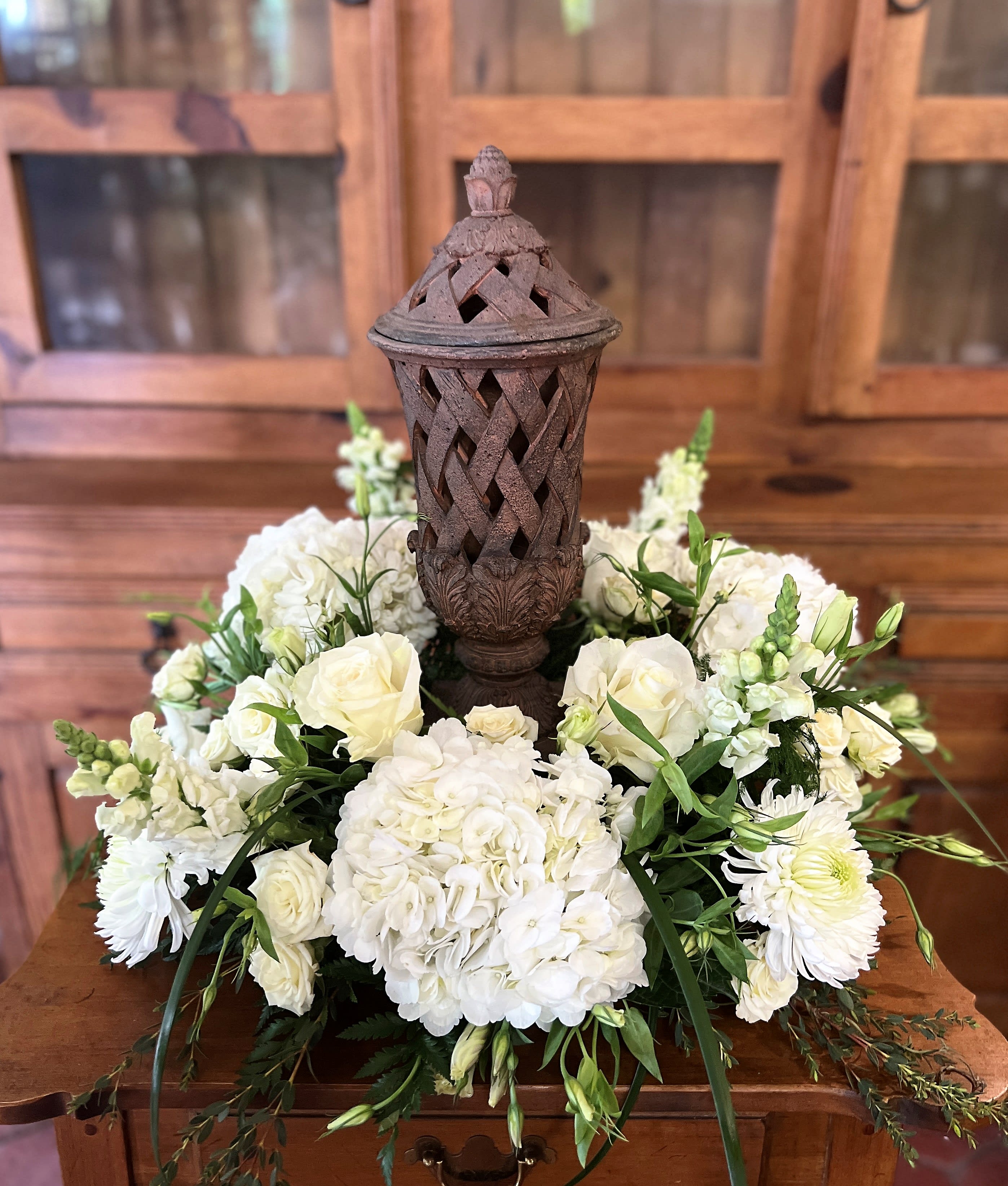 White floral arrangement around a decorative lantern centerpiece