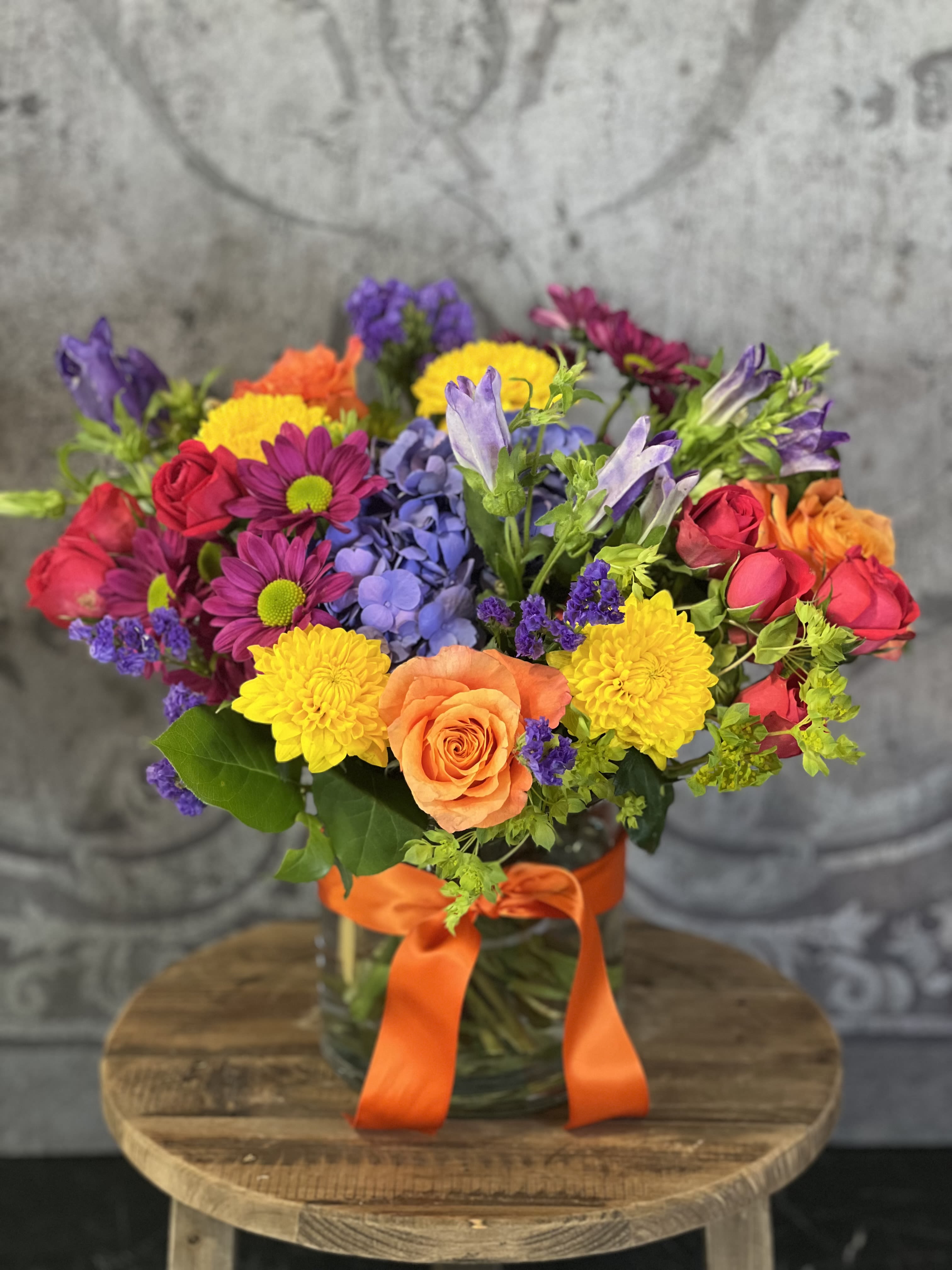 Colorful mixed bouquet in a glass vase with an orange ribbon