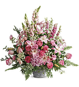 Tall arrangement of pink lilies, roses, and snapdragons in a gray urn-style vase