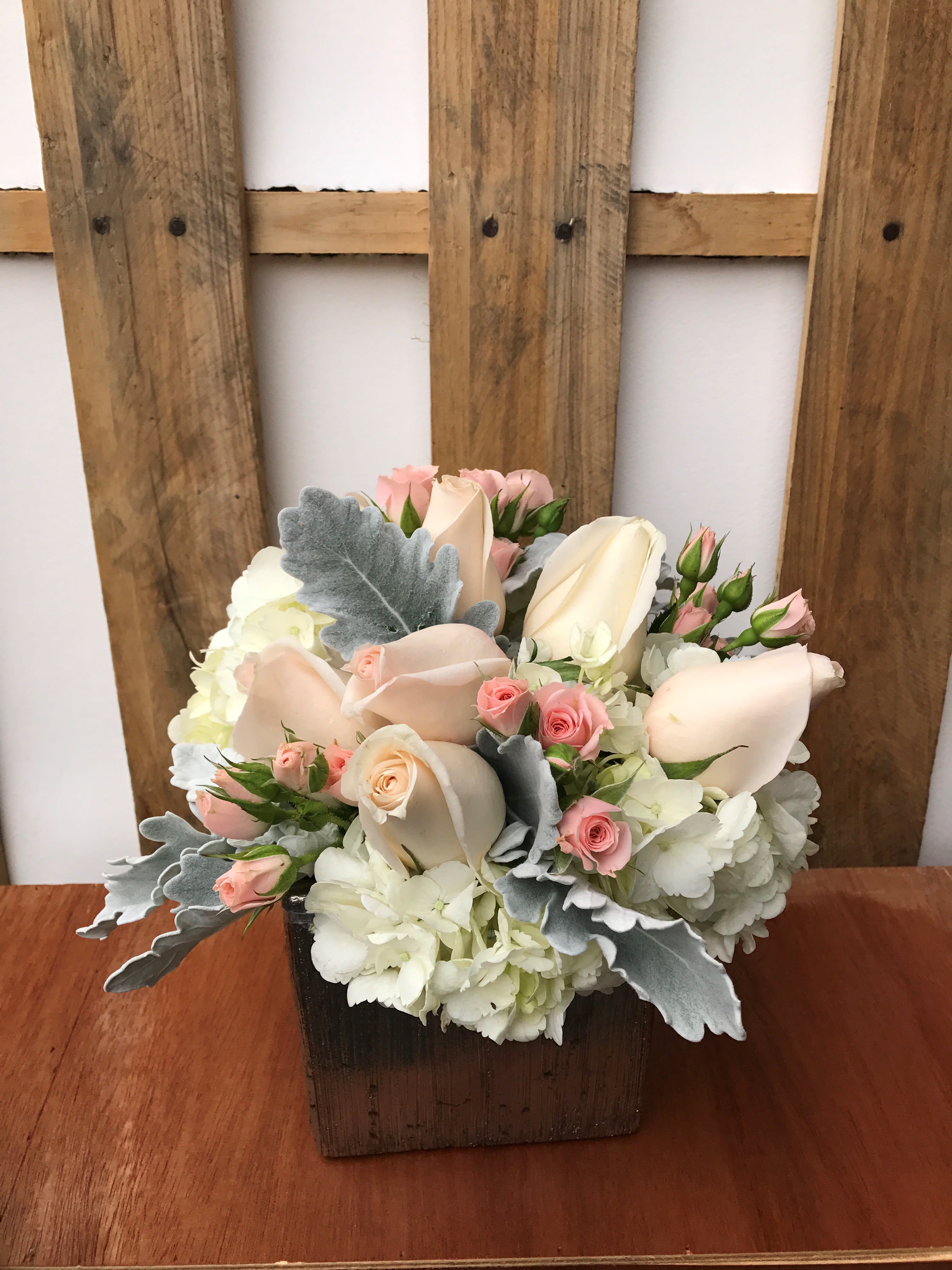 Pastel roses and hydrangeas arranged in a wooden box