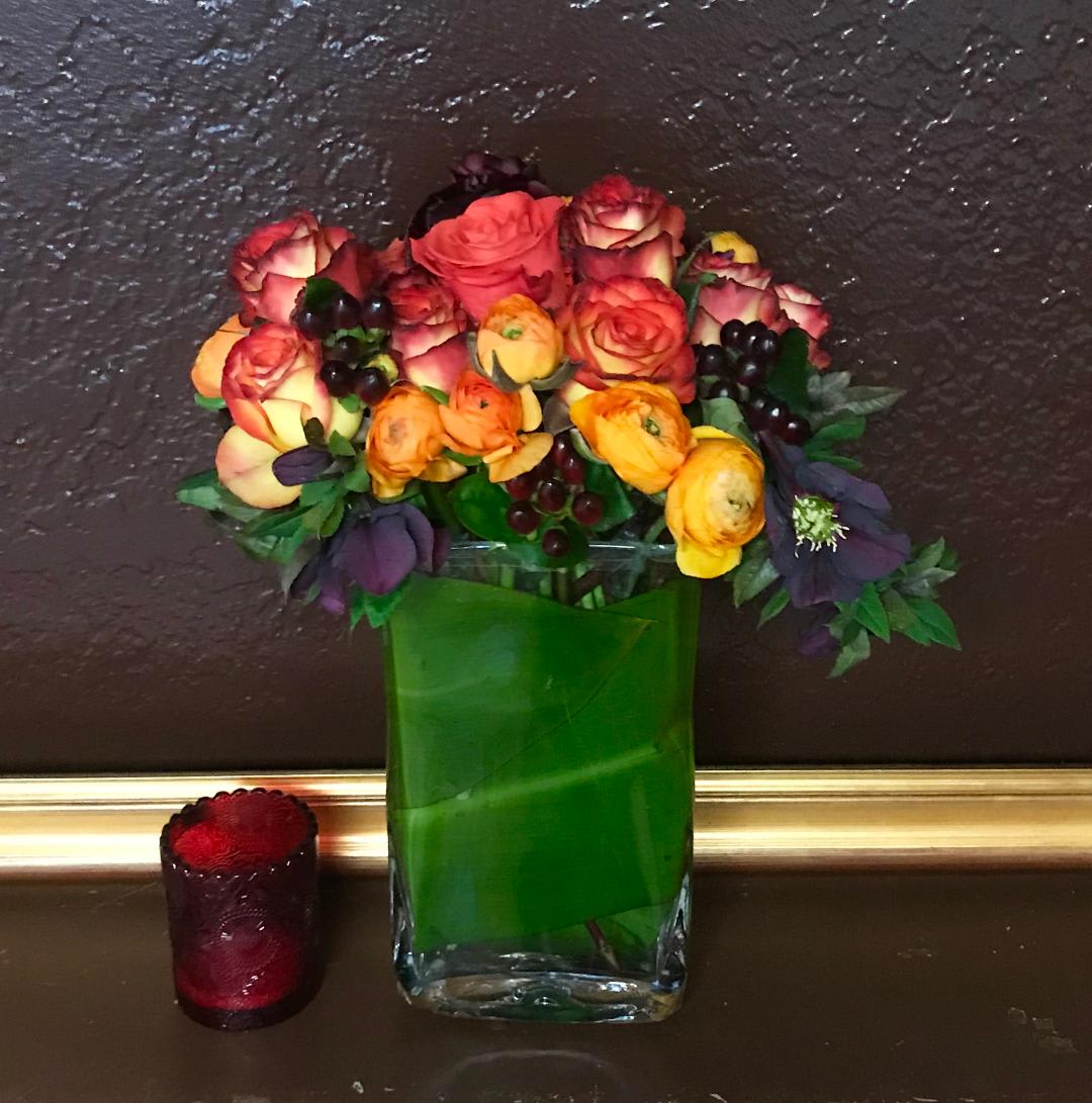 Mixed bouquet of roses and ranunculus in a clear glass vase
