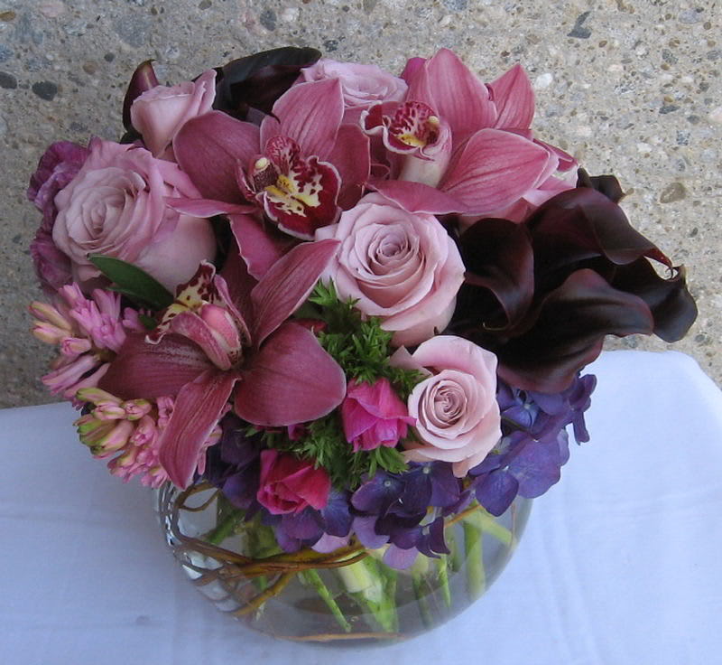 Pink and purple bouquet with roses, orchids, and calla lilies in a glass vase