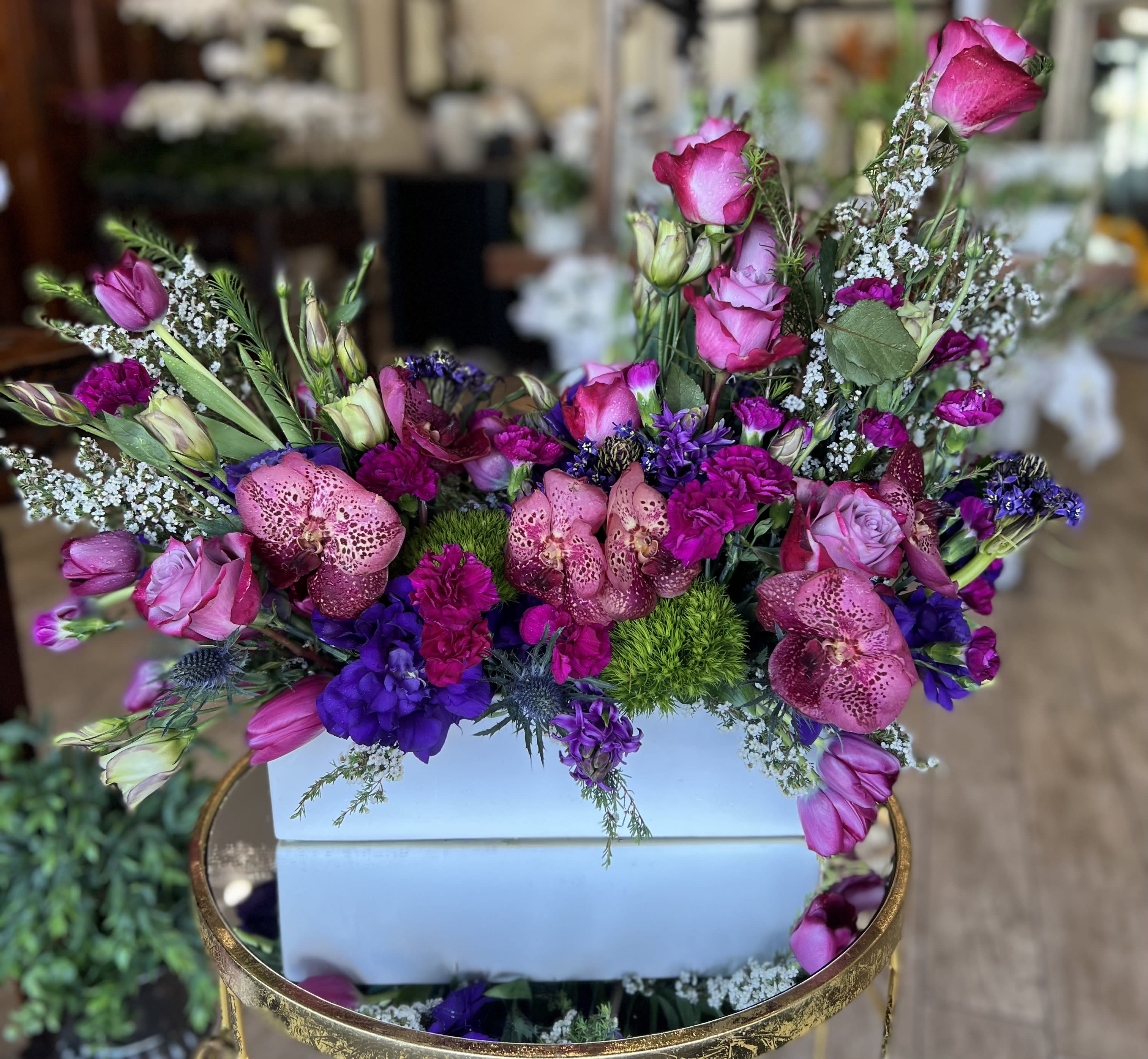 Mixed pink and purple floral arrangement in a white box