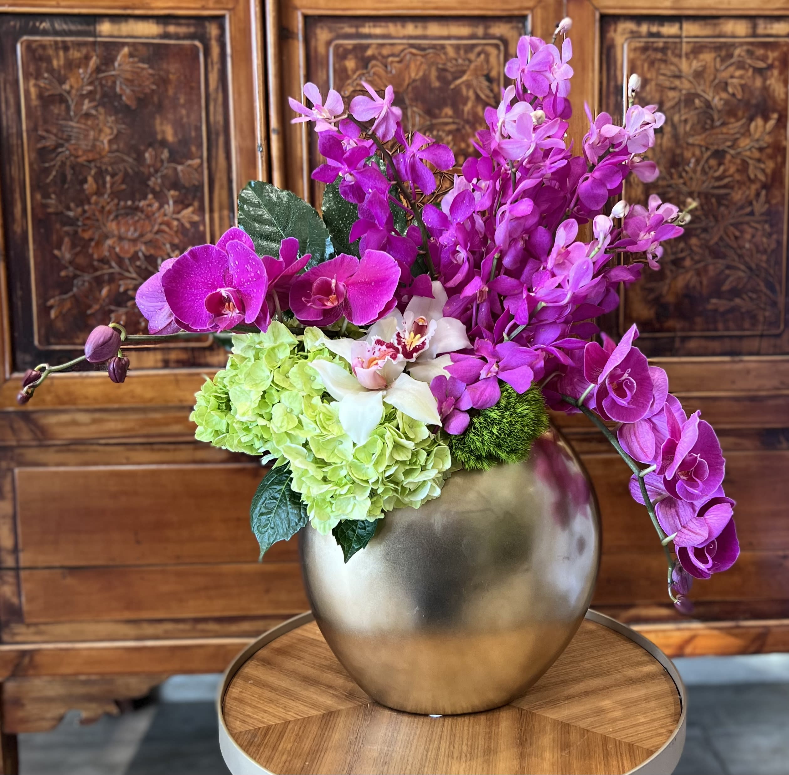 Pink orchids and green hydrangeas in a gold vase