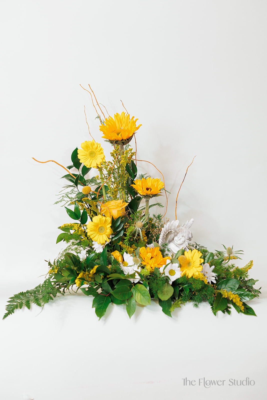 Yellow and white floral arrangement with a small angel figurine