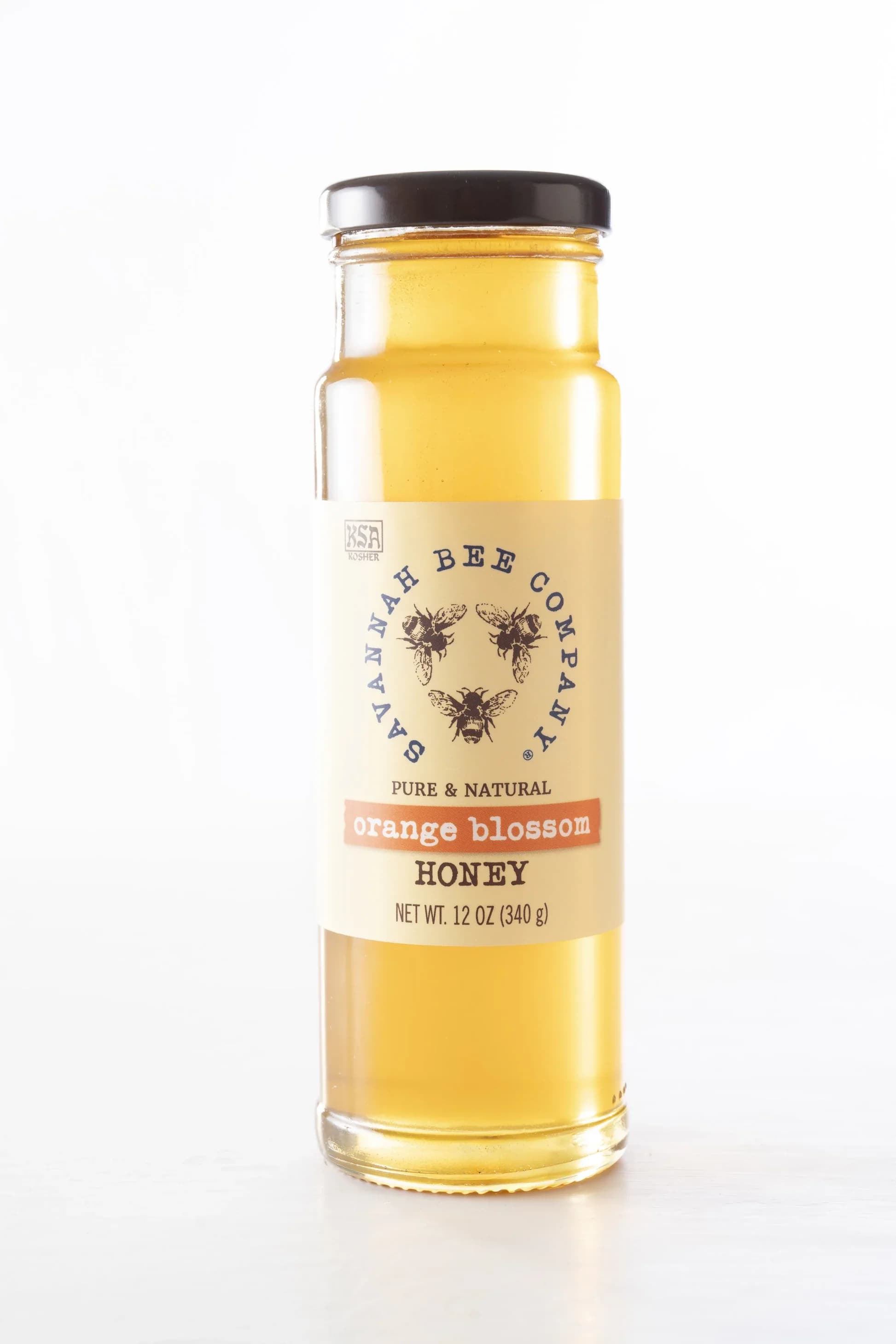 A jar of orange blossom honey with a black lid and labeled front