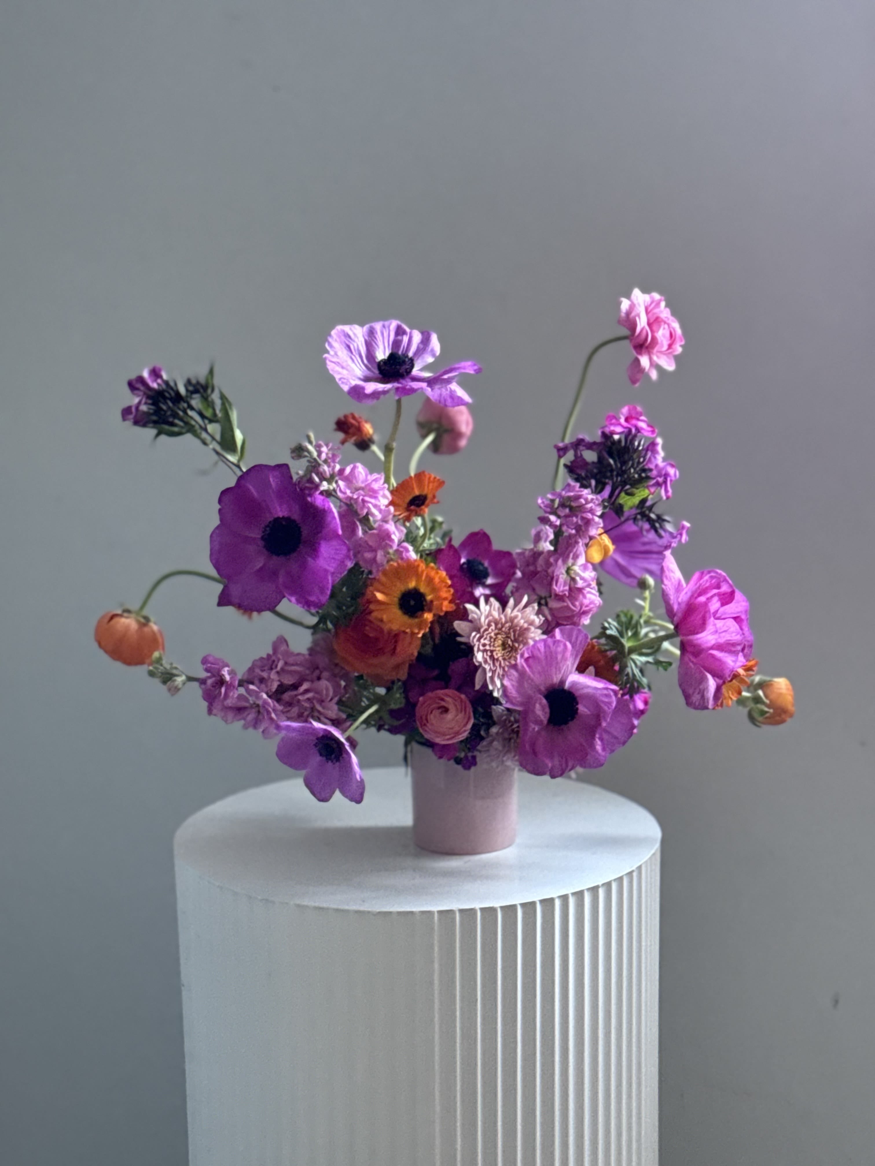 A small vase arrangement of purple, pink, and orange flowers